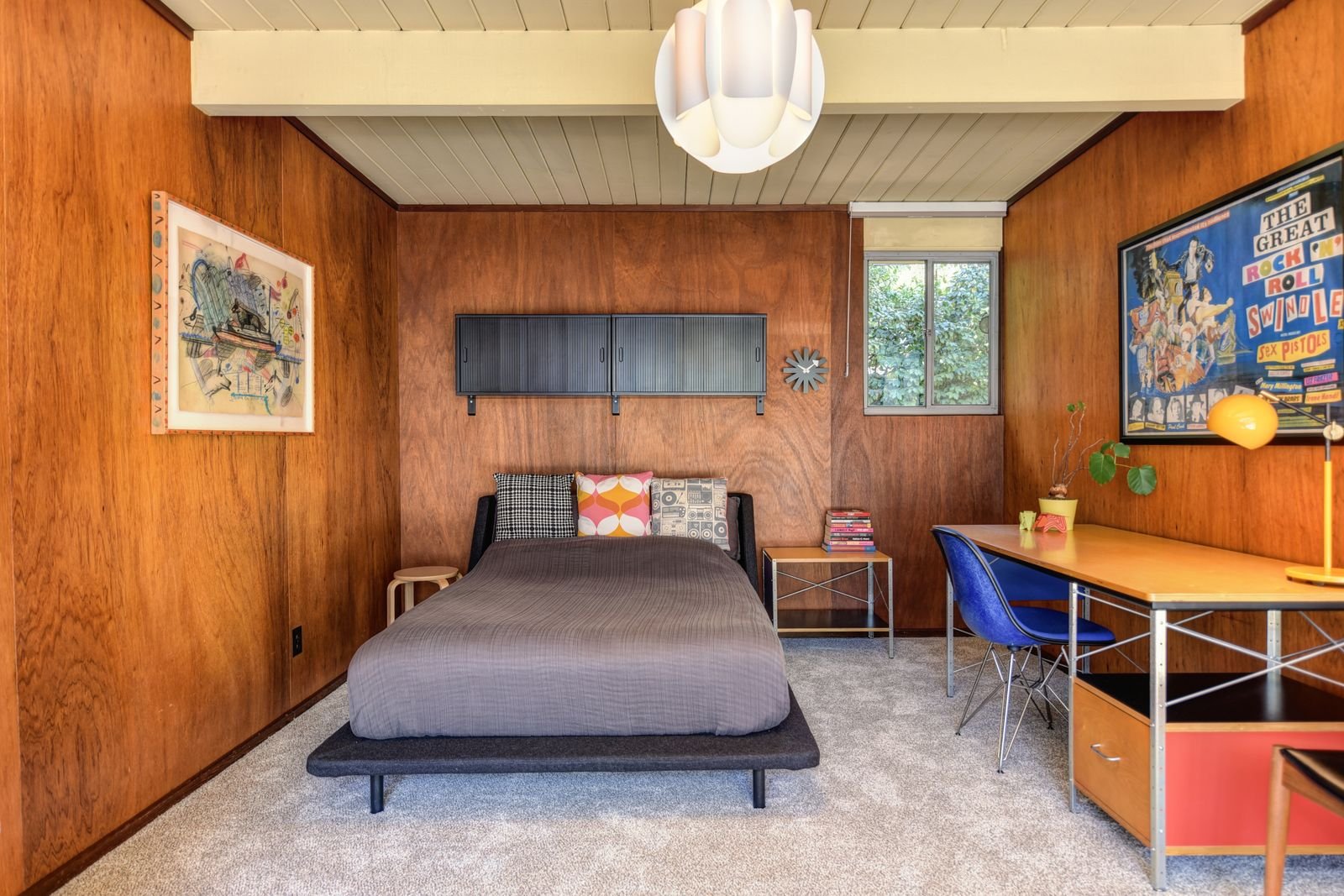 Mid-century bedroom with wood-paneled walls and a bed.