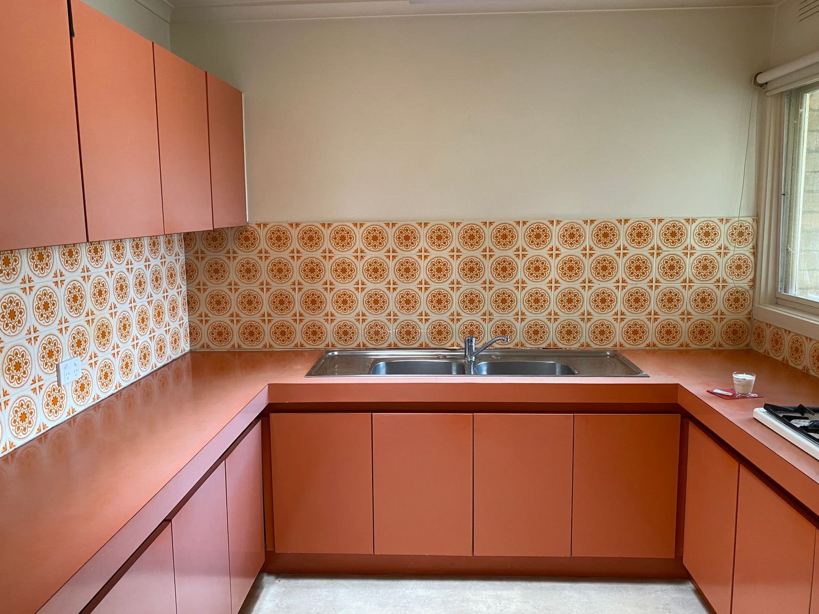 Vintage kitchen with orange cabinets and patterned tiles.