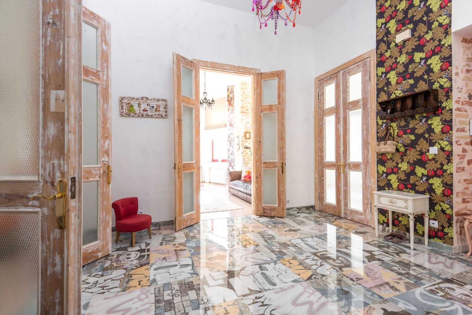 Eclectic room with a colorful floor, wooden doors and bold wallpaper.