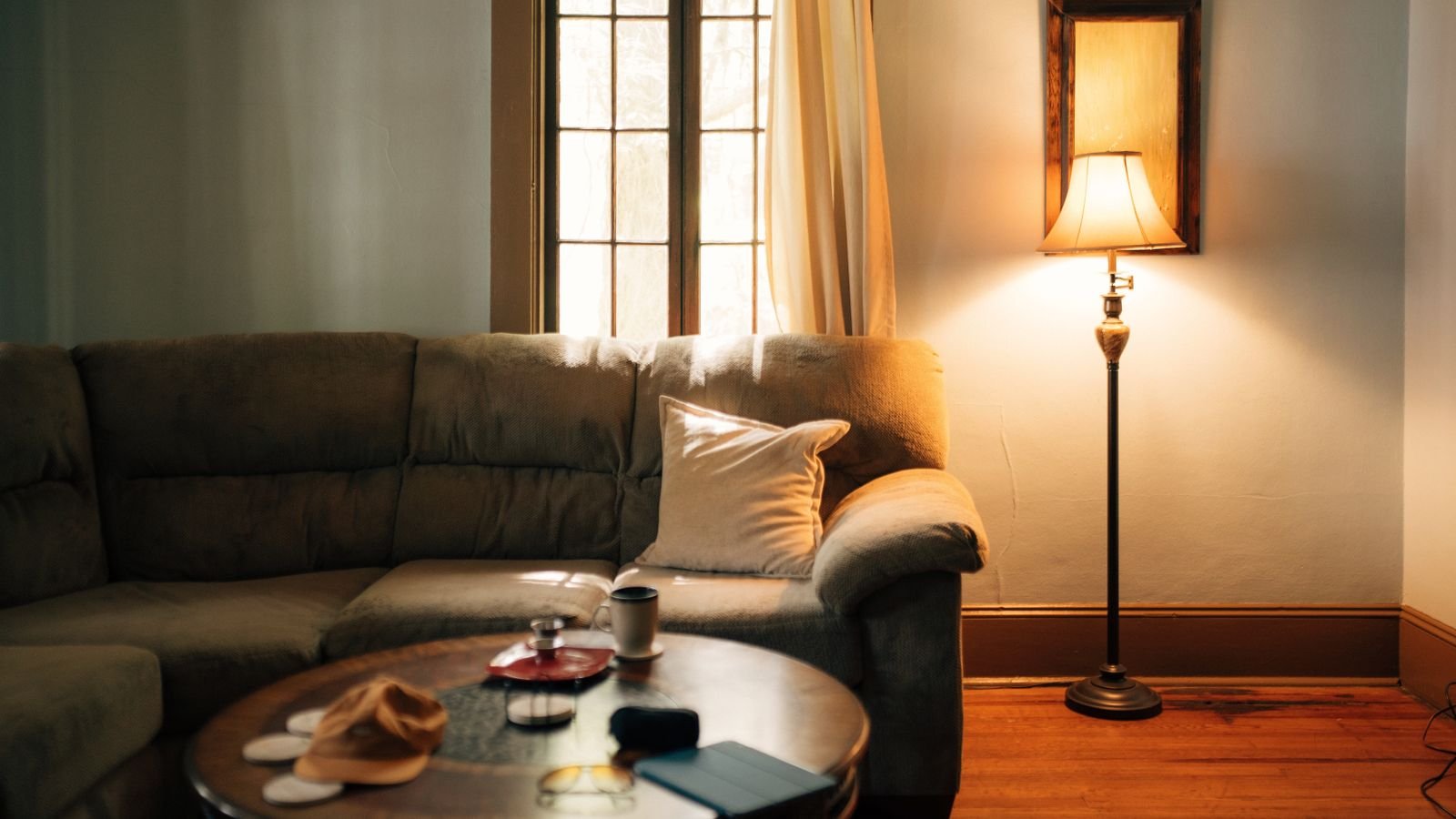 Floor lamp glowing beside a sofa and coffee table in a warmly lit living room
