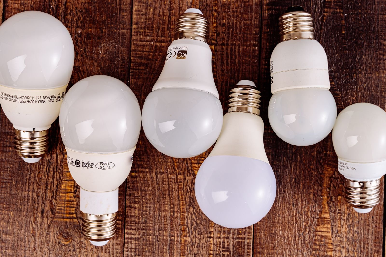 Row of energy-efficient LED light bulbs lined up on a wooden surface