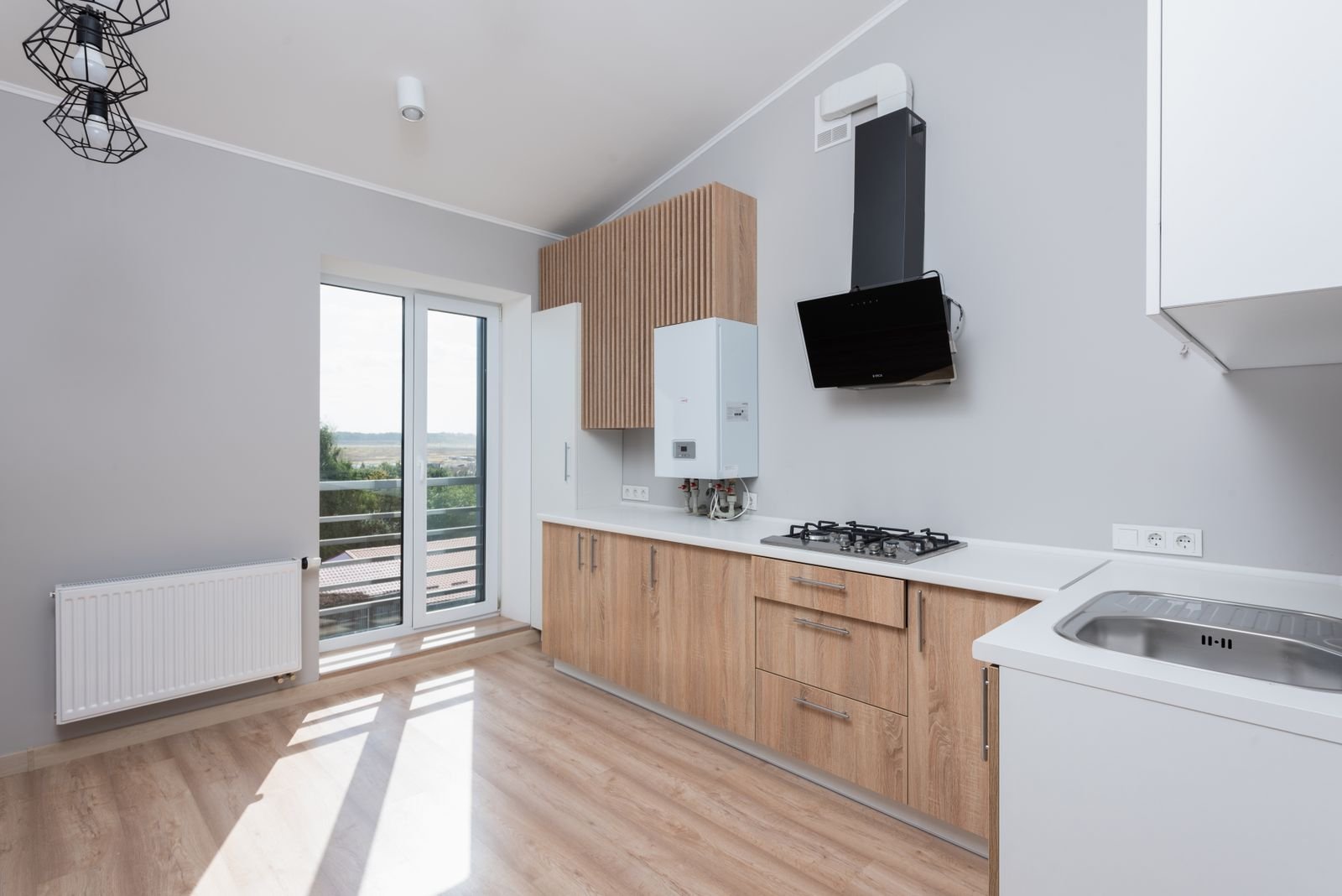 Kitchen with wooden cabinets lit by natural light from large windows