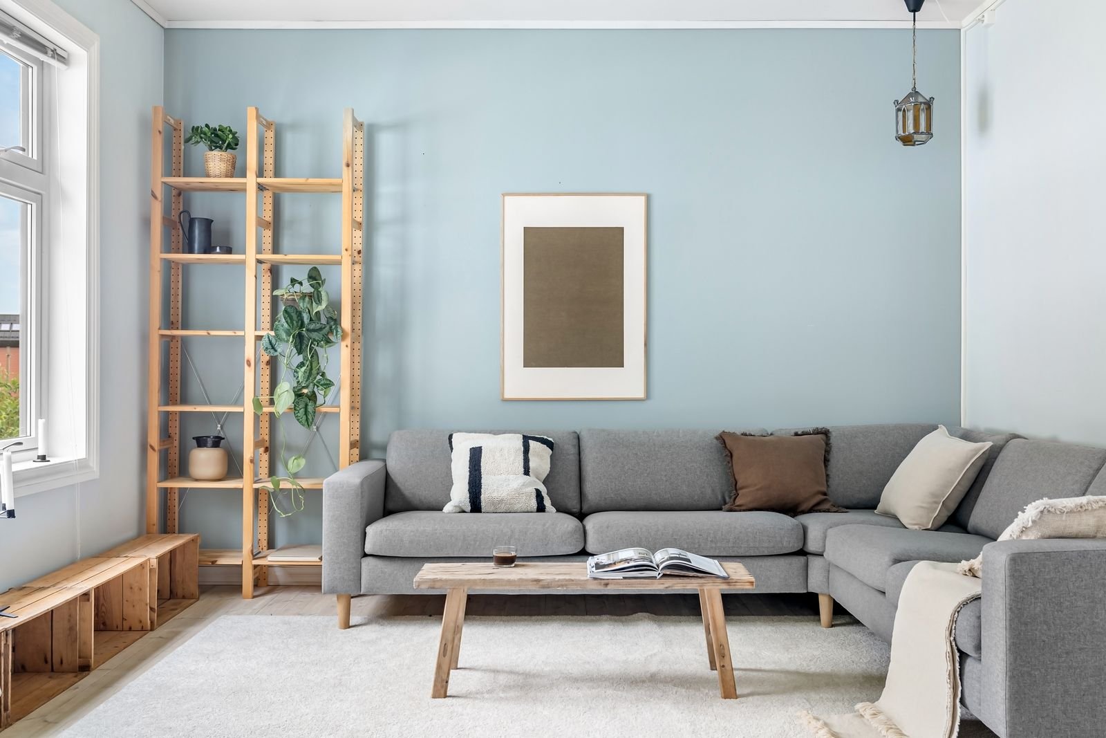 Scandinavian living room with a gray sofa, light walls and warm wooden accents