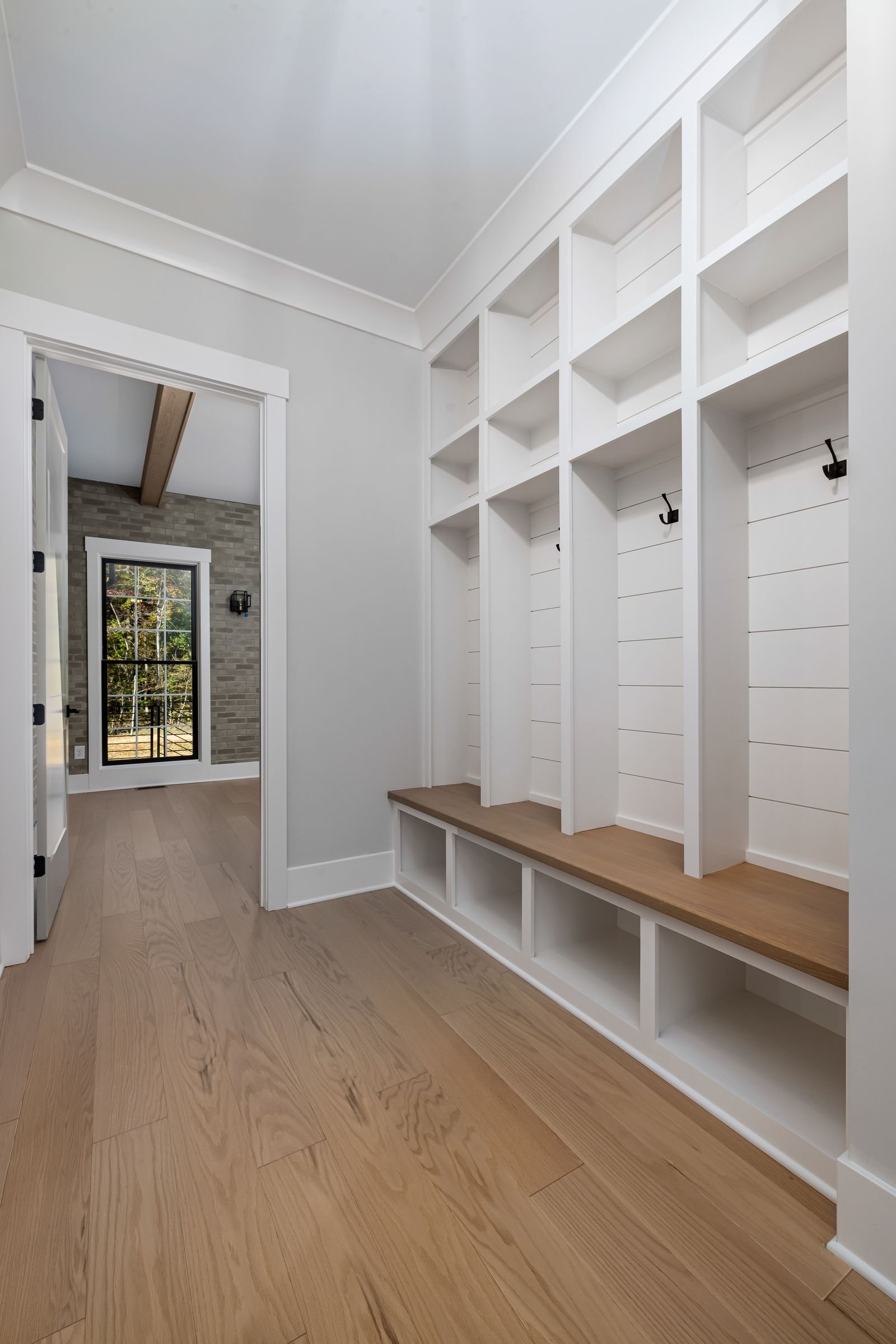 Bright entryway with white built-in shelves and a wood floor