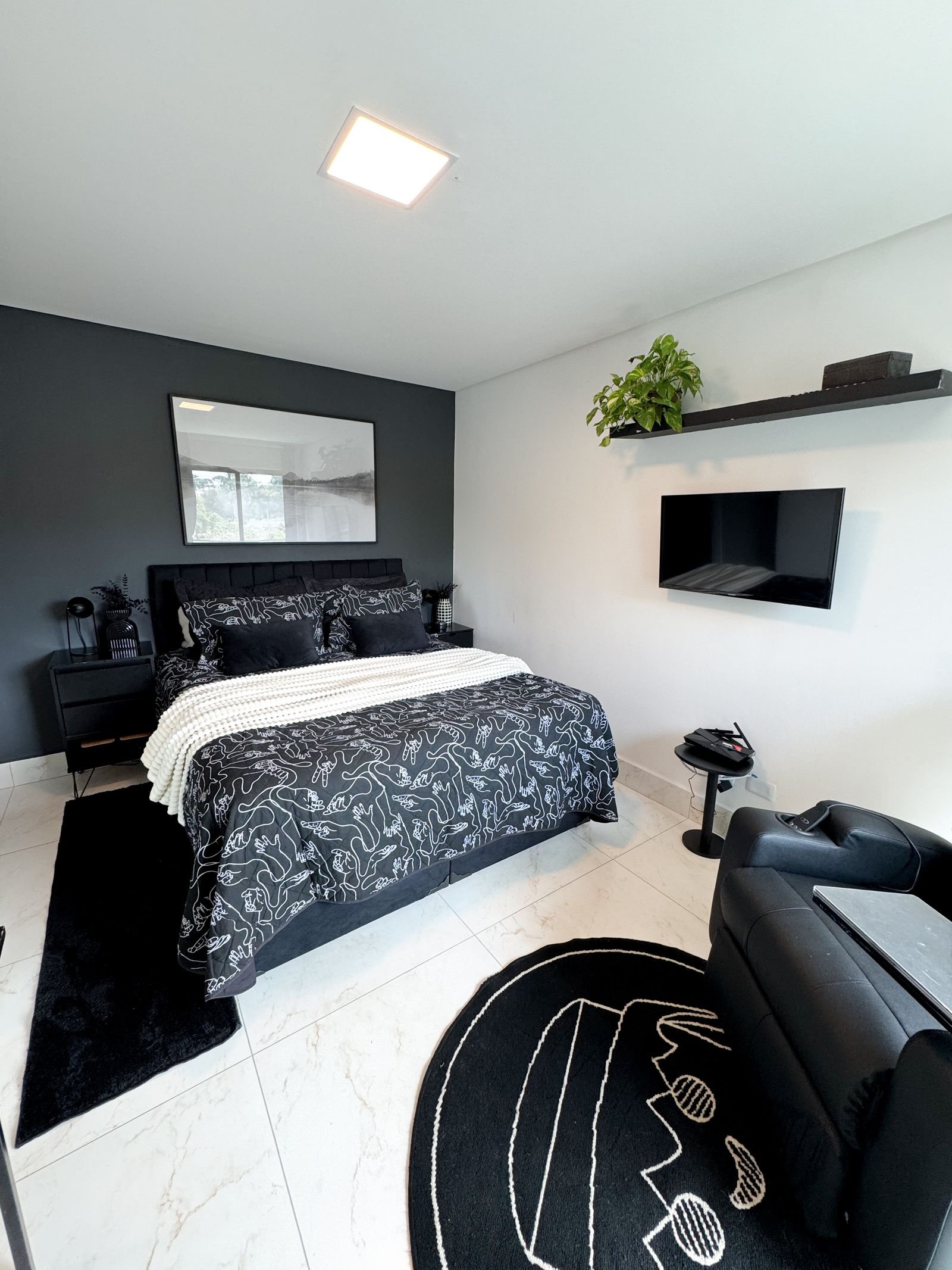 Minimalist bedroom styled in black and white with a few green plants