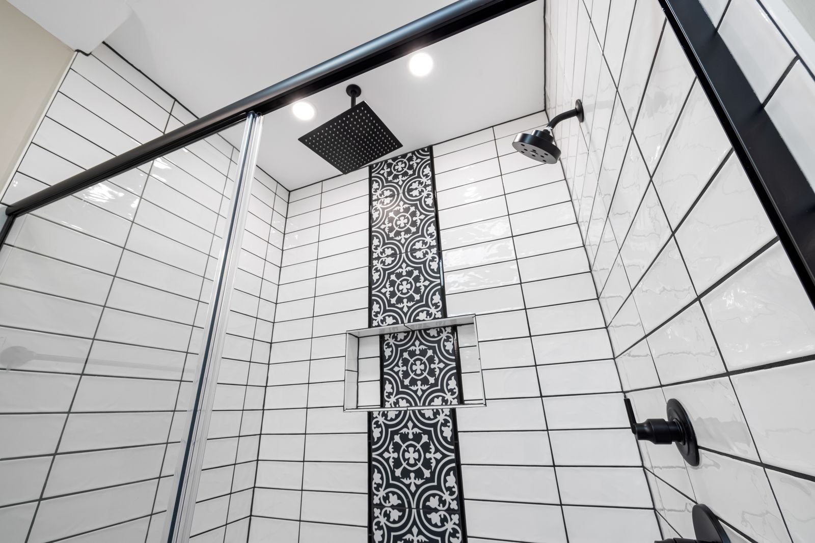 Bathroom shower with a bold patterned tile wall and black fixtures