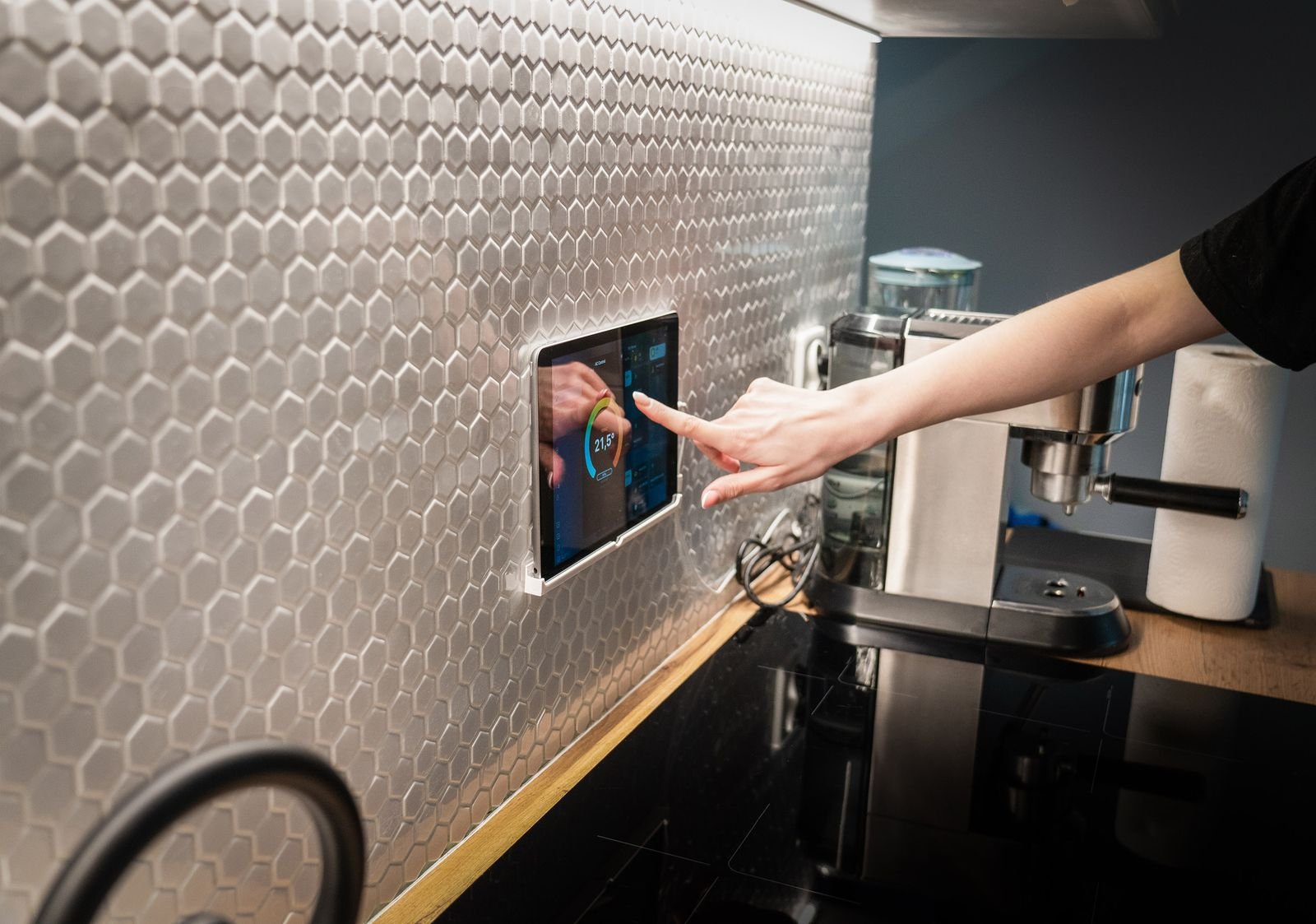 Modern kitchen with a touchscreen smart home control panel set into a hexagon-patterned wall