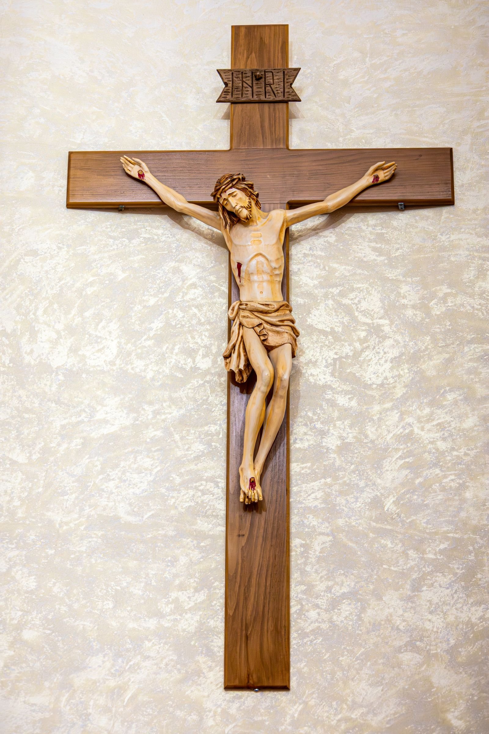 Carved wooden crucifix hanging on a textured wall