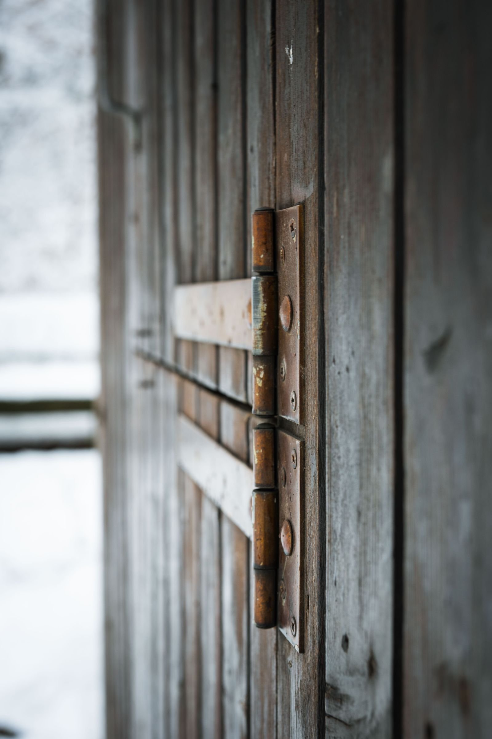 Old rusty metal hinges on an aged wooden door