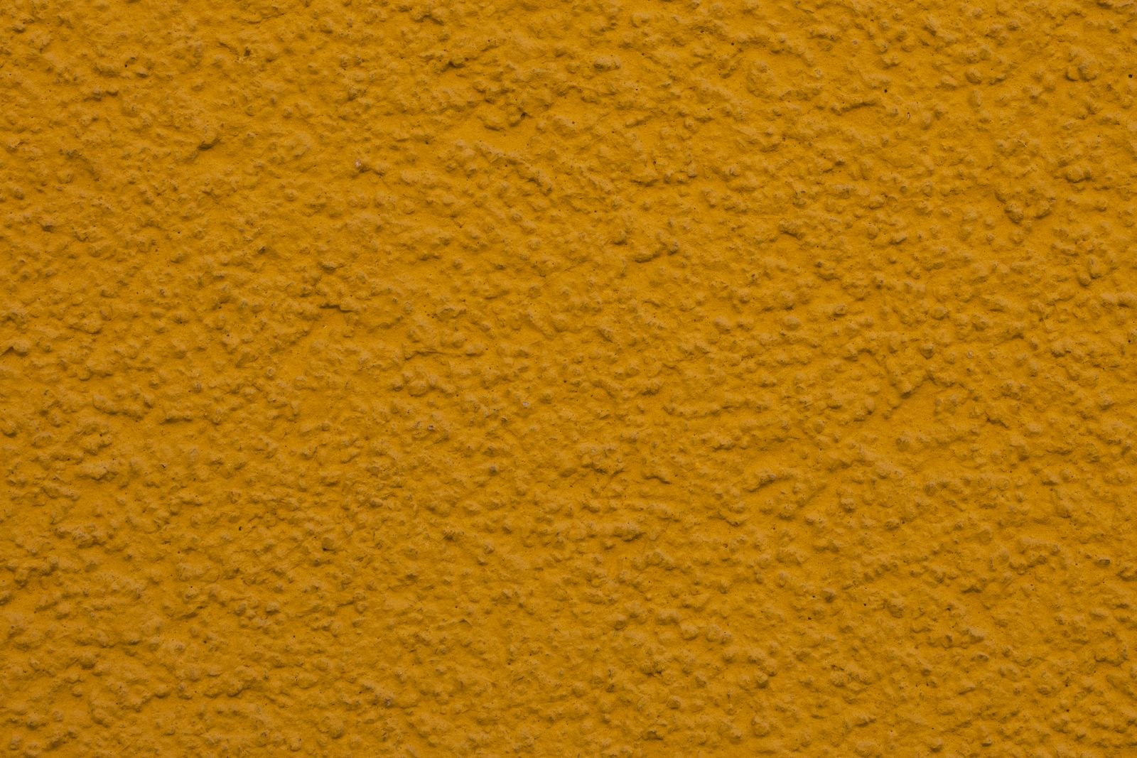 Close-up of a textured yellow plaster wall finish