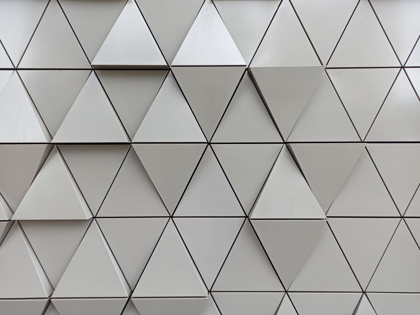 Close-up of three-dimensional triangular tiles forming a textured geometric wall pattern