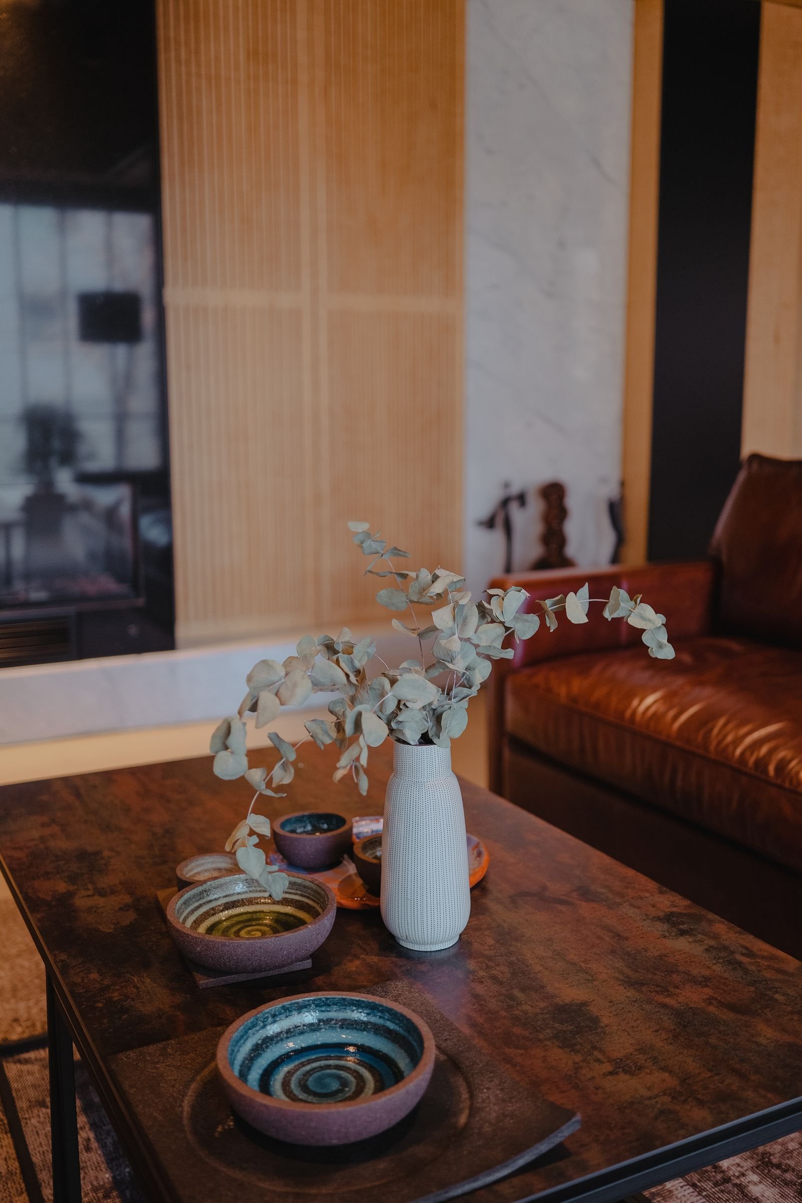 Designer coffee table styled with decorative plates and a vase of eucalyptus