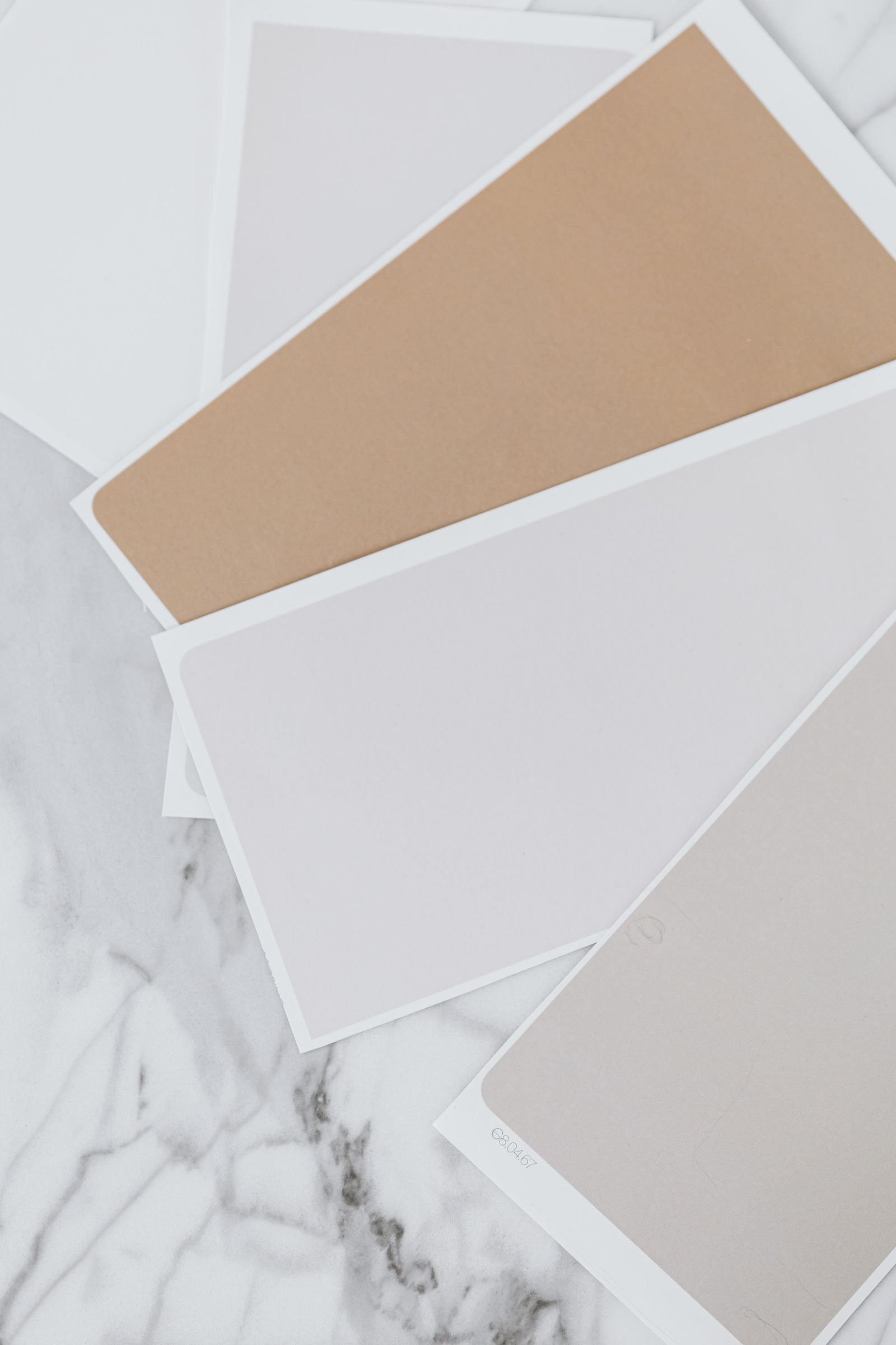 Beige and grey paint color samples laid out on a marble table