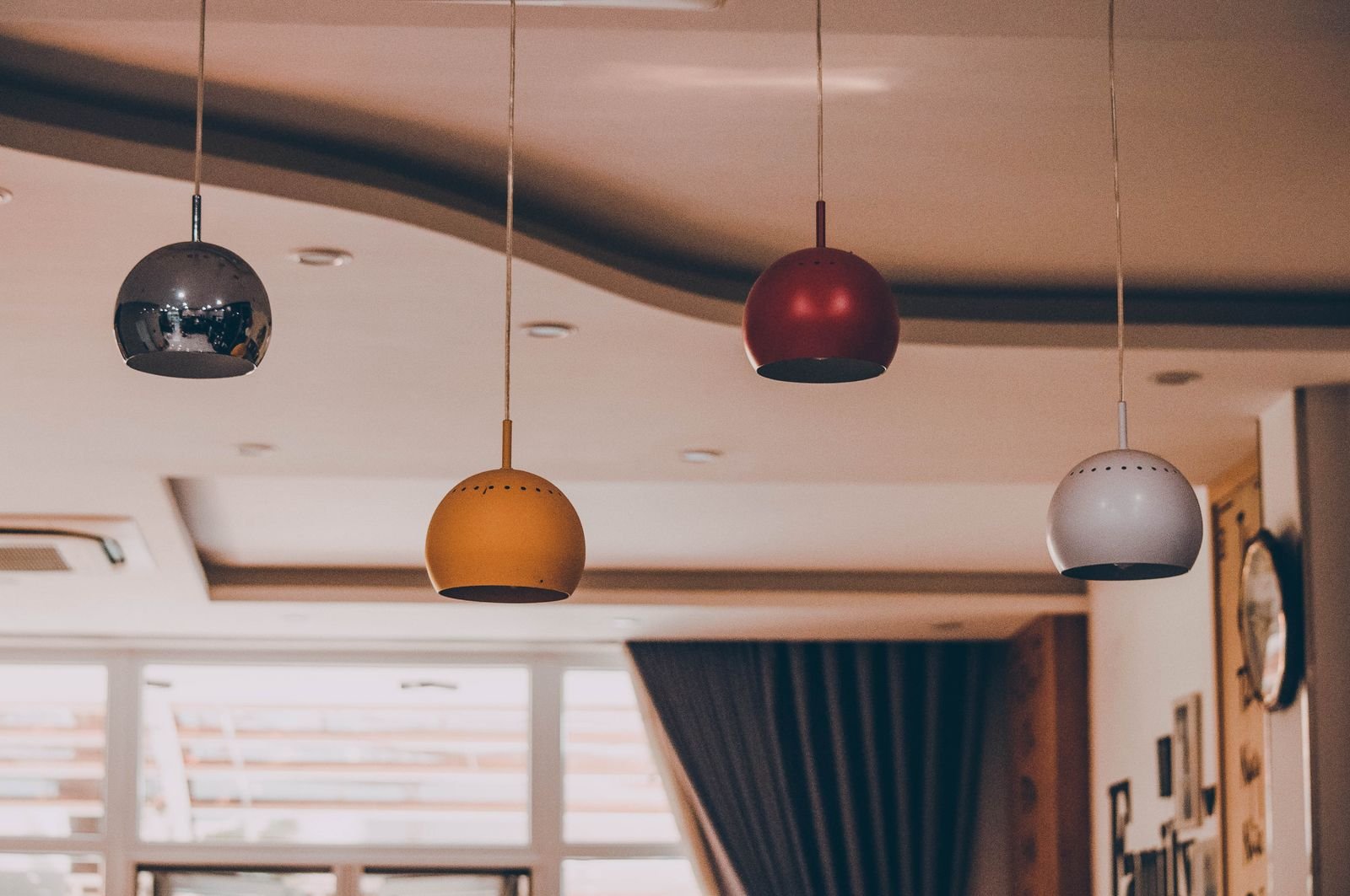 Colorful pendant lamps hanging from a patterned ceiling for a playful lighting look