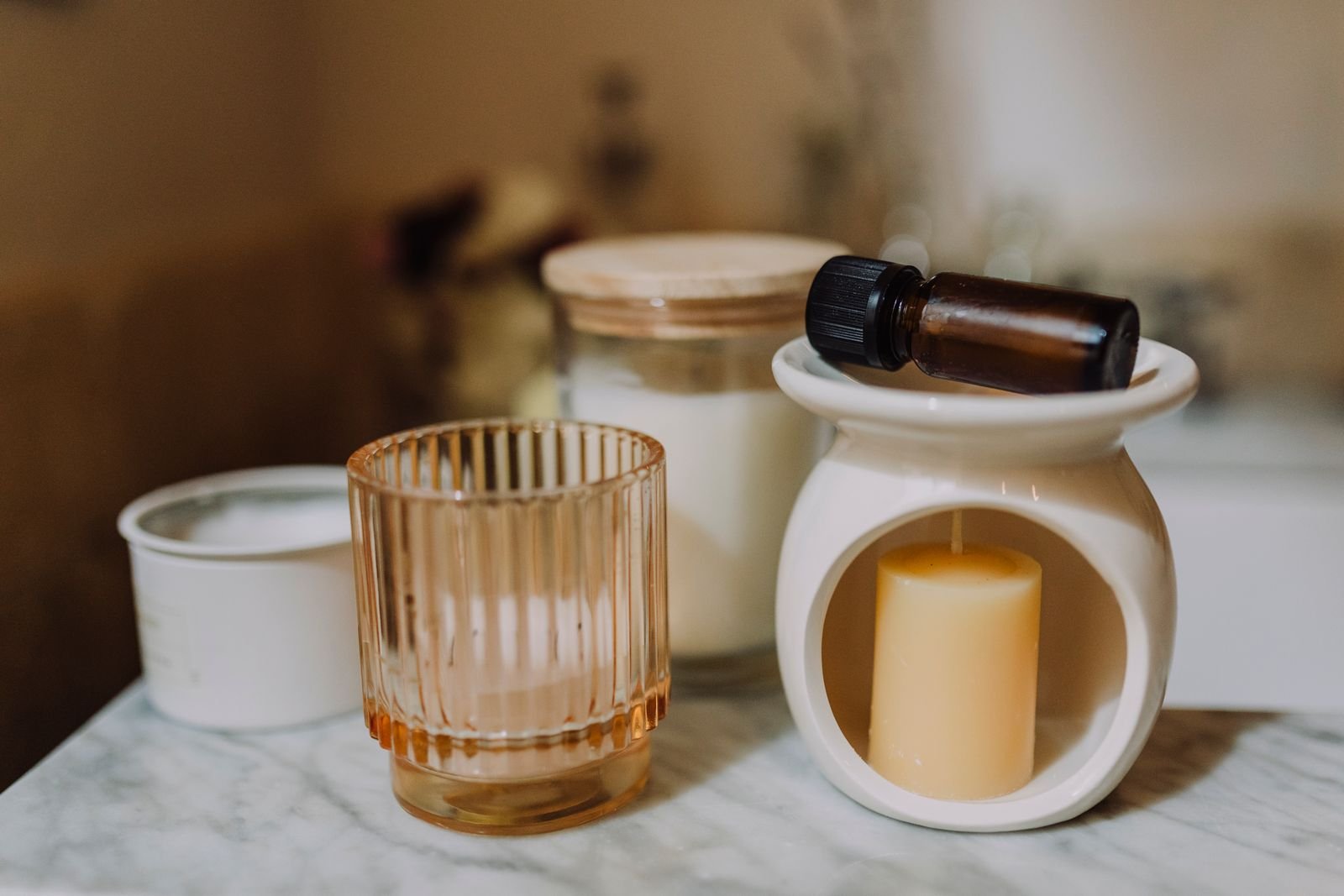 Scented candles in glass and ceramic jars with essential oil on marble