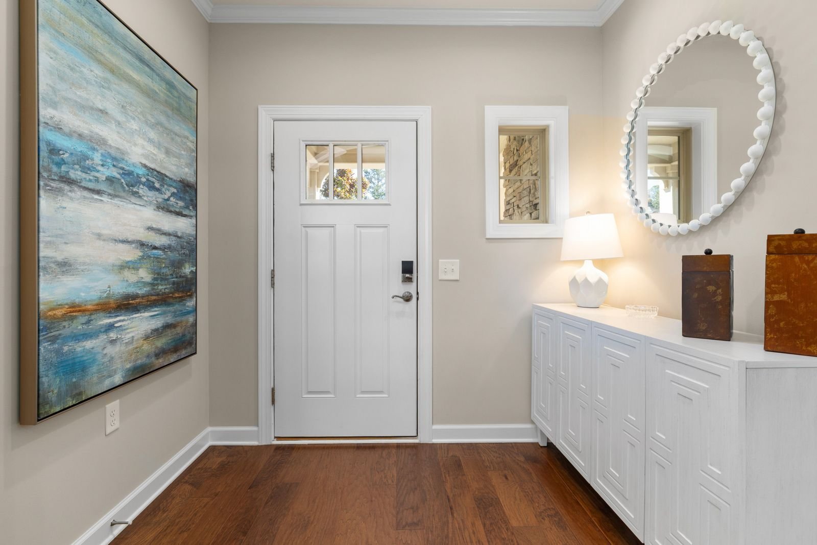 Bright entryway with abstract wall art beside a white front door