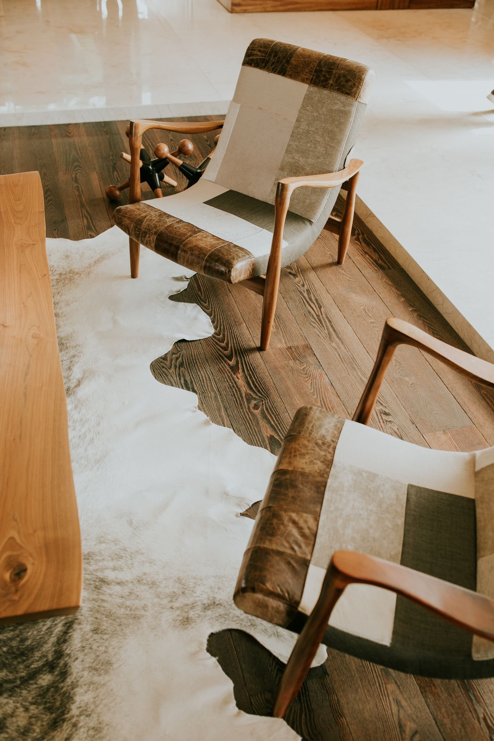 Patchwork armchairs on a cowhide rug in a modern room.
