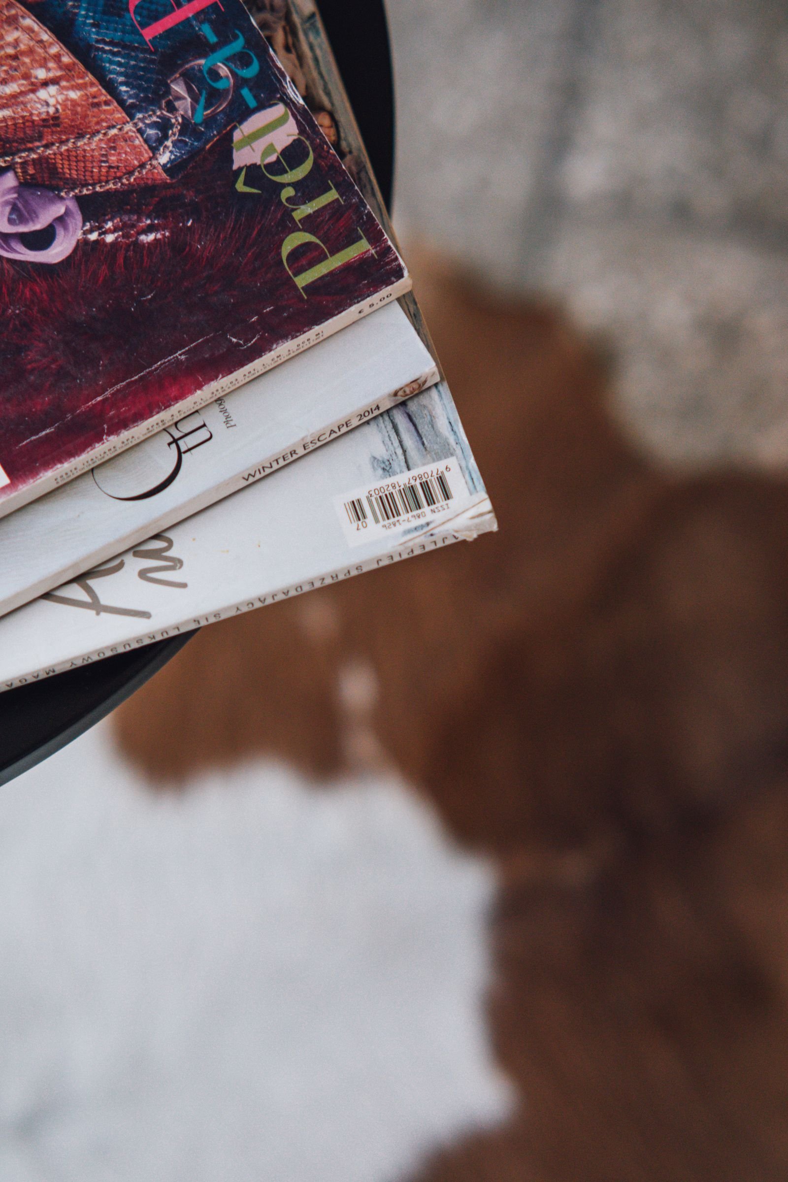 Stack of magazines on a table above a cowhide rug.