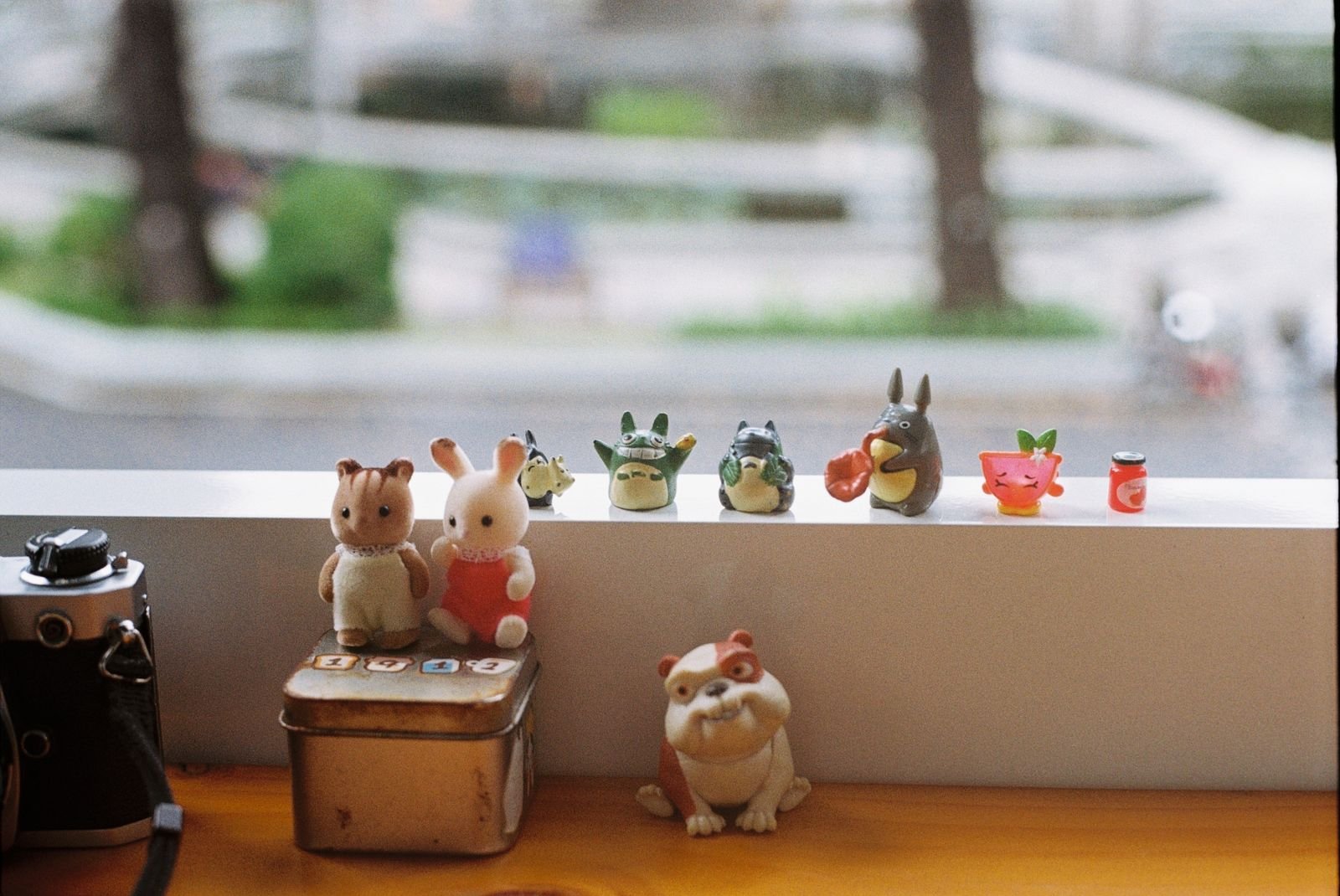 Small toy figurines arranged on a shelf by a window.
