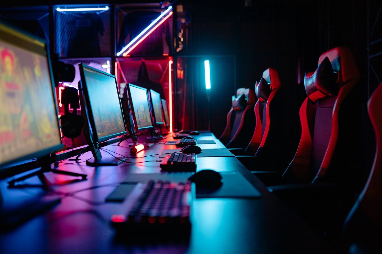 Neon-lit room with computers and gaming chairs.