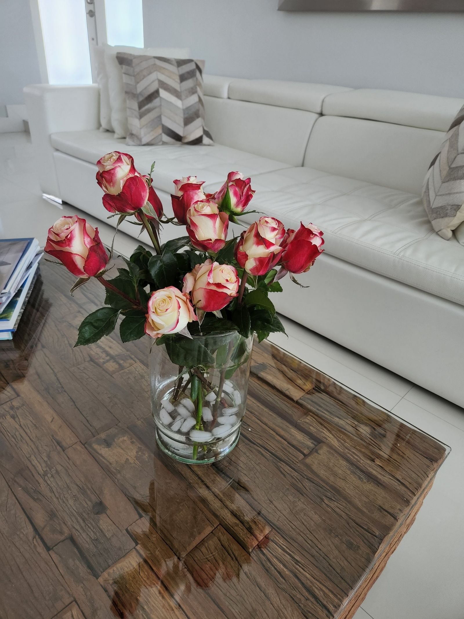 Pink and white roses in a vase on a wooden coffee table.