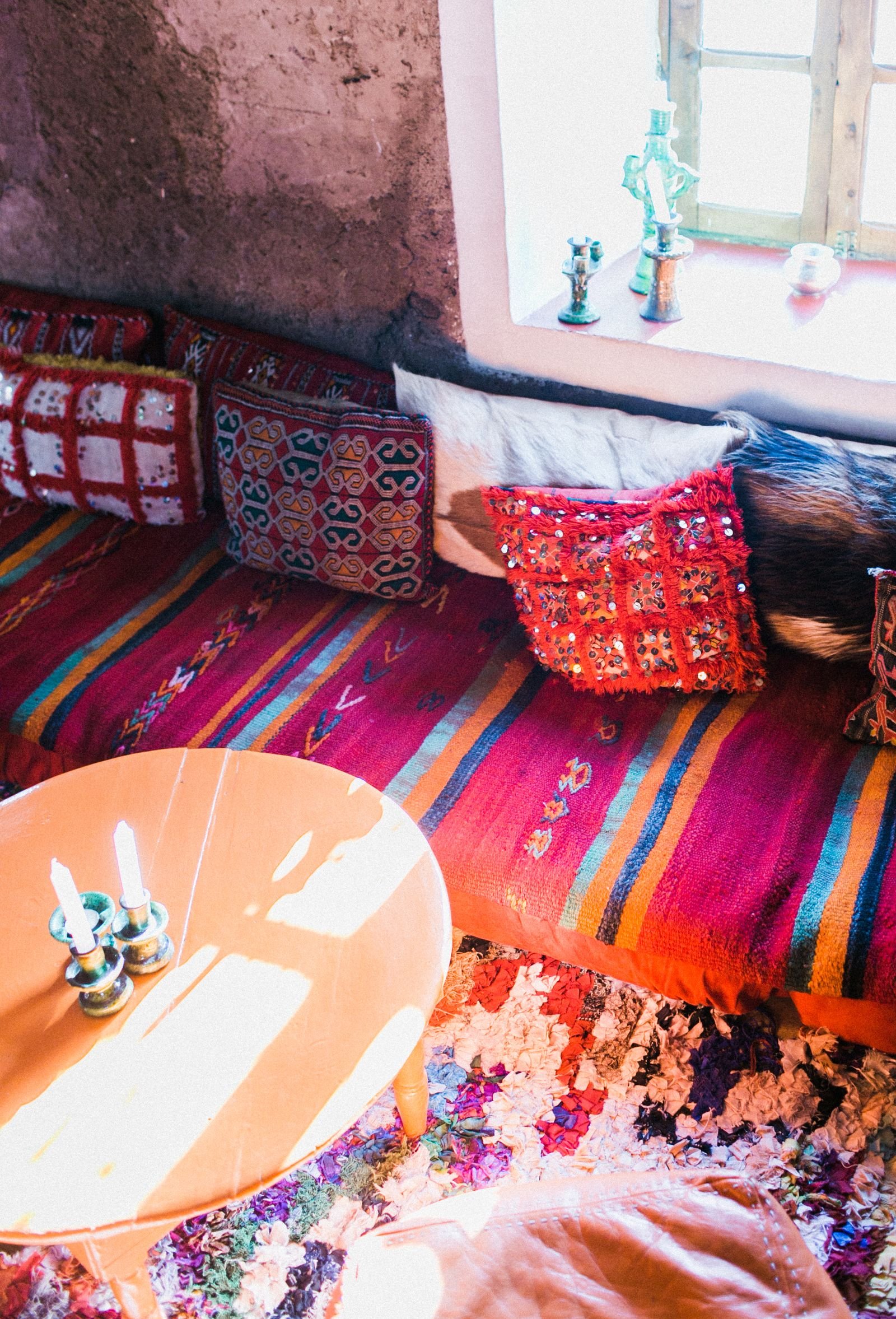 Multicolored floor cushions and candles in an oriental-style room.