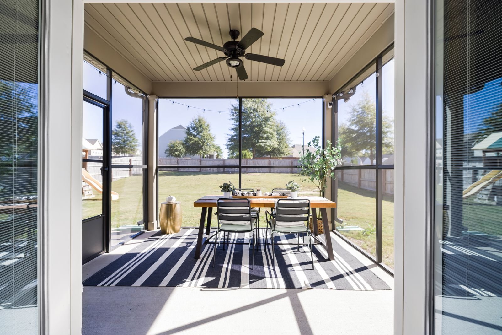 Bright terrace with a wooden dining table and chairs overlooking a garden.