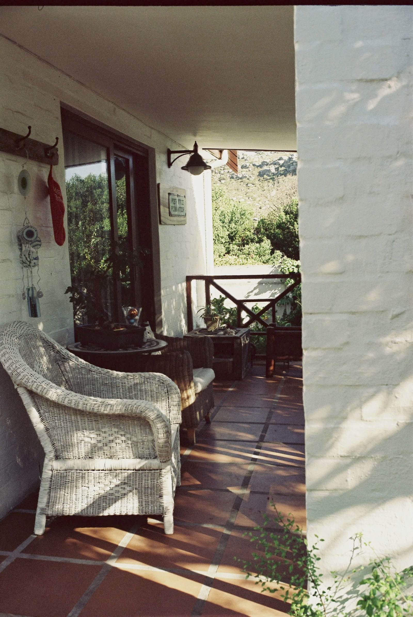 Porch with a wicker chair and wooden furniture overlooking a garden.