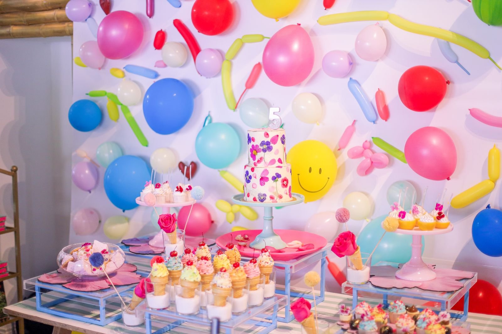 Birthday dessert table decorated with balloons and cake.