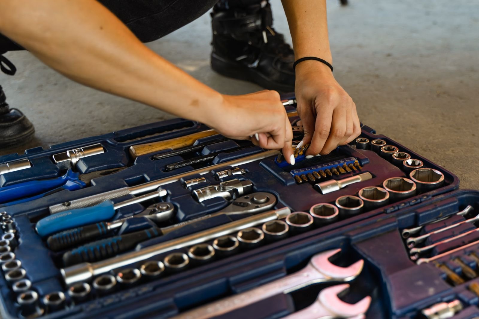 Hands choosing a tool from a well-organized toolbox.