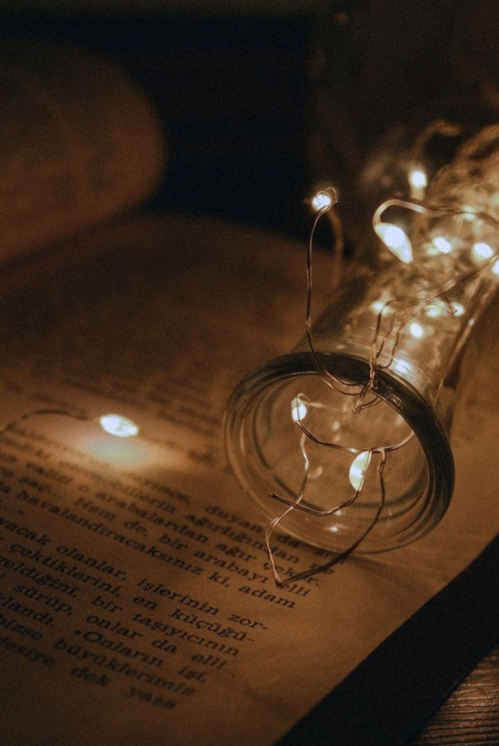 Fairy lights glowing from a jar over an open book.