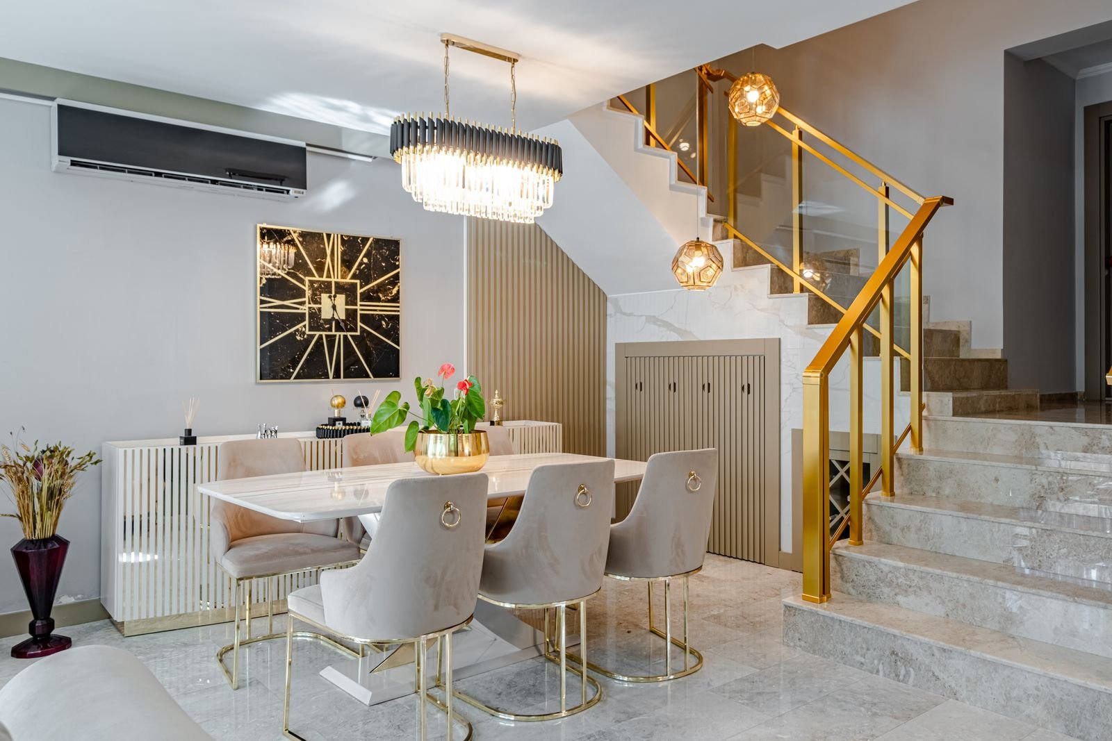 Dining room with a marble table, gold accents and stylish lighting.