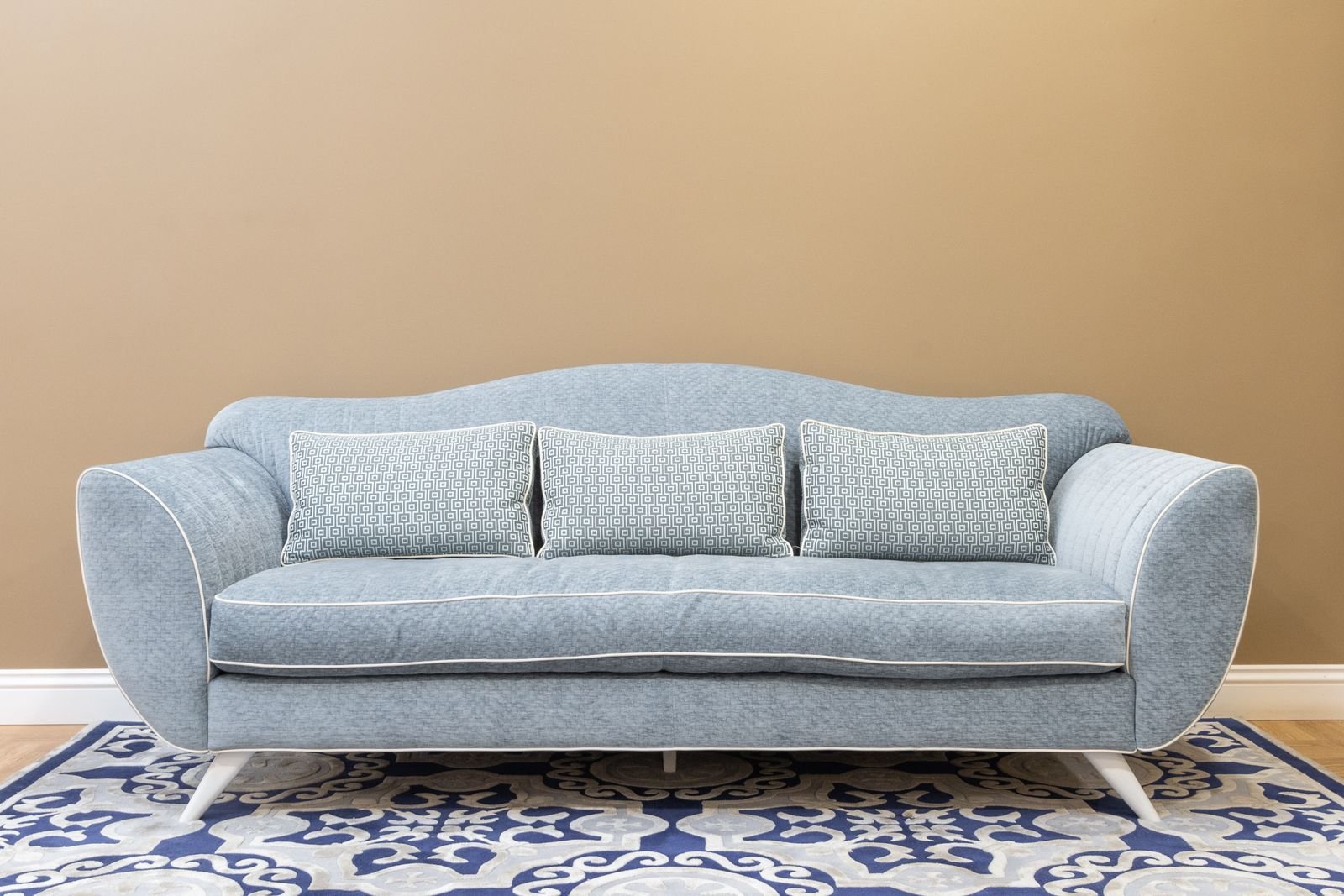 Blue sofa with cushions on a patterned carpet in a cozy living room.