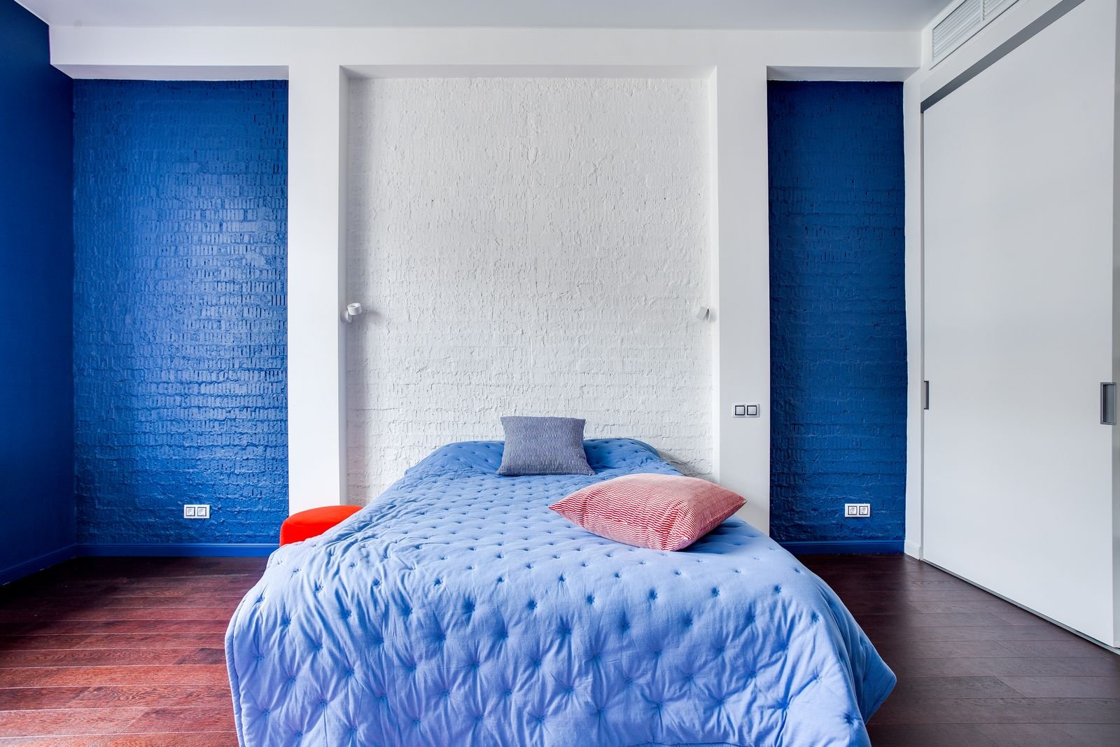 Modern bedroom with navy walls, a cozy bed and stylish pillows.
