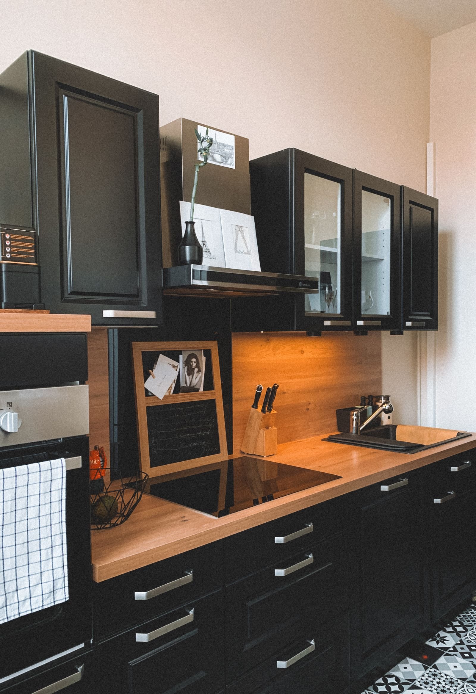 Modern kitchen with black cabinets and a wooden countertop.