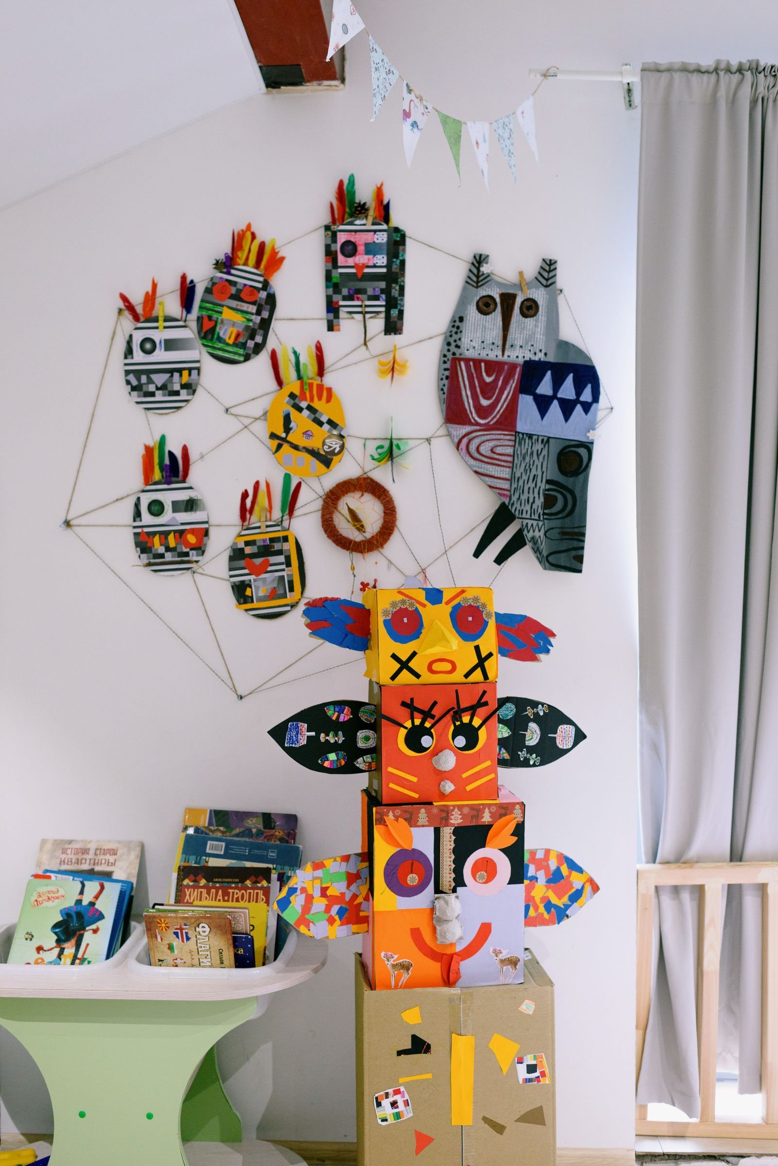 Bright kids' room with handmade cardboard toys and drawings on the wall.