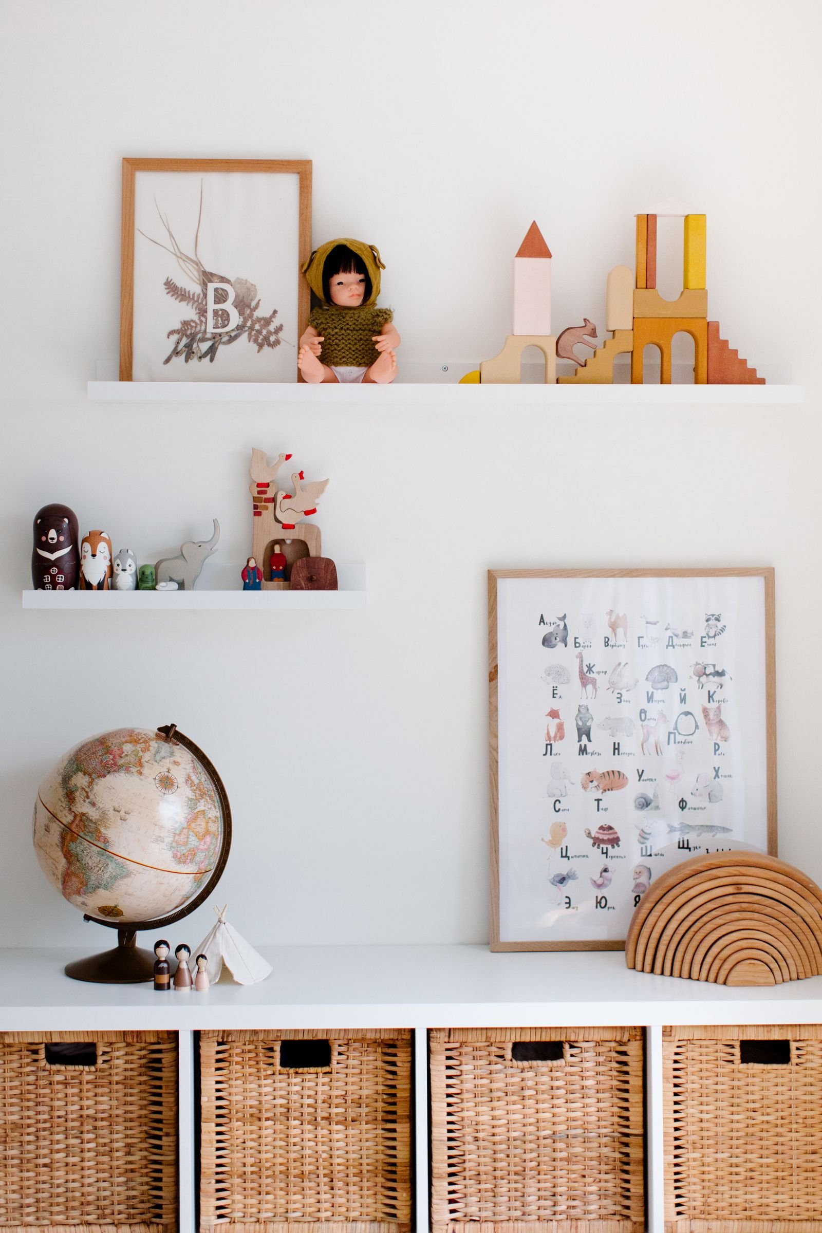 Child's room with white shelves holding toys, paintings and a globe.