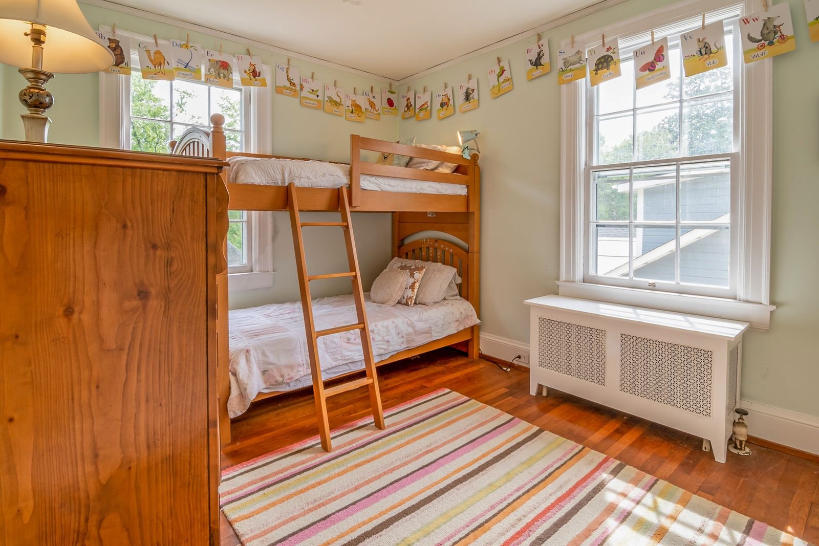 Children's bedroom with wooden bunk beds and natural light.