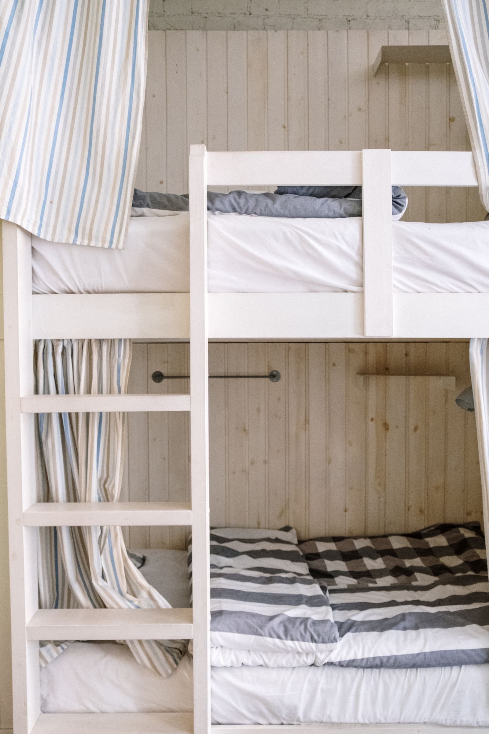 Minimalist wooden bunk bed with striped bedding.