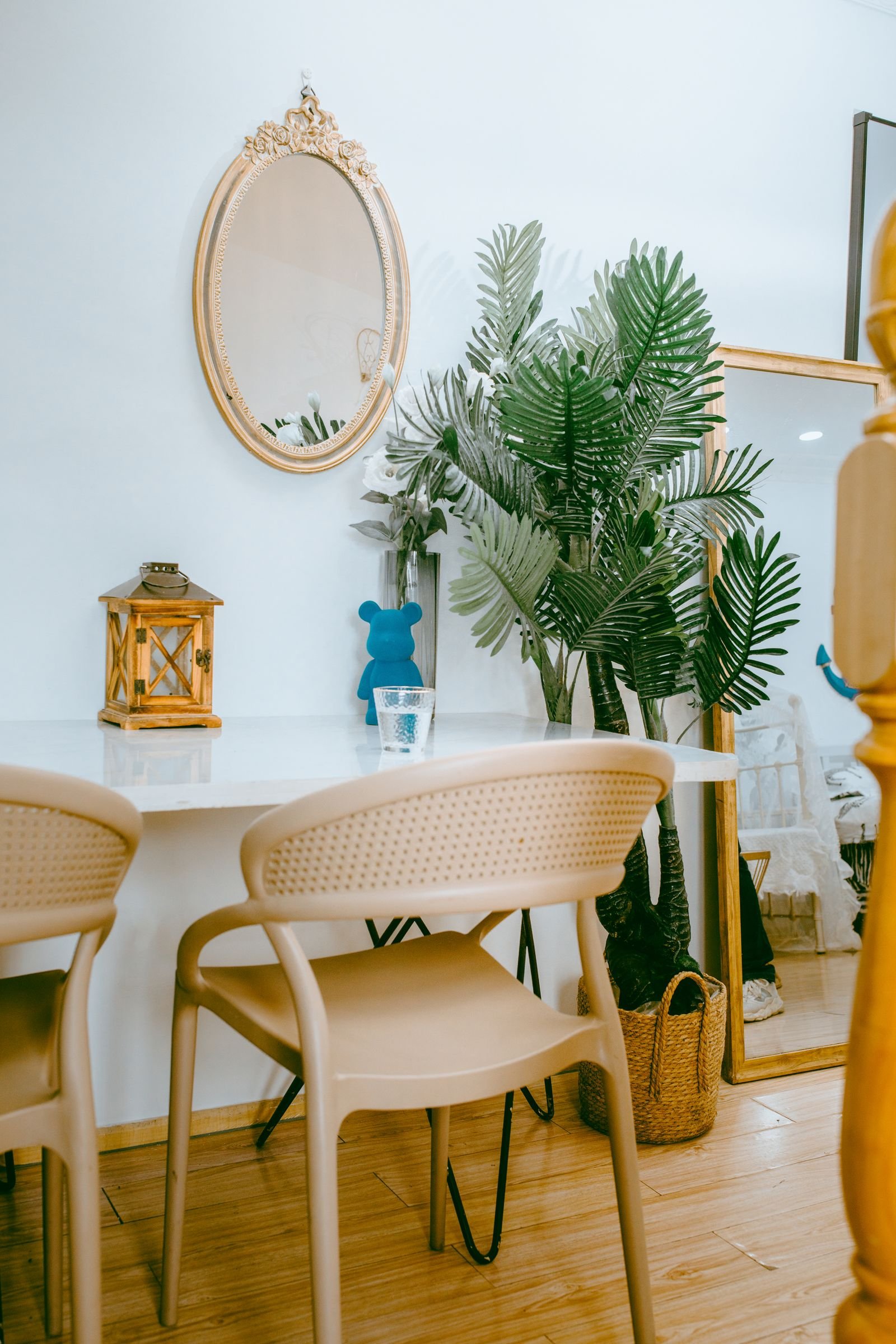 Minimalist interior with a mirror over a table, chairs and green plants.