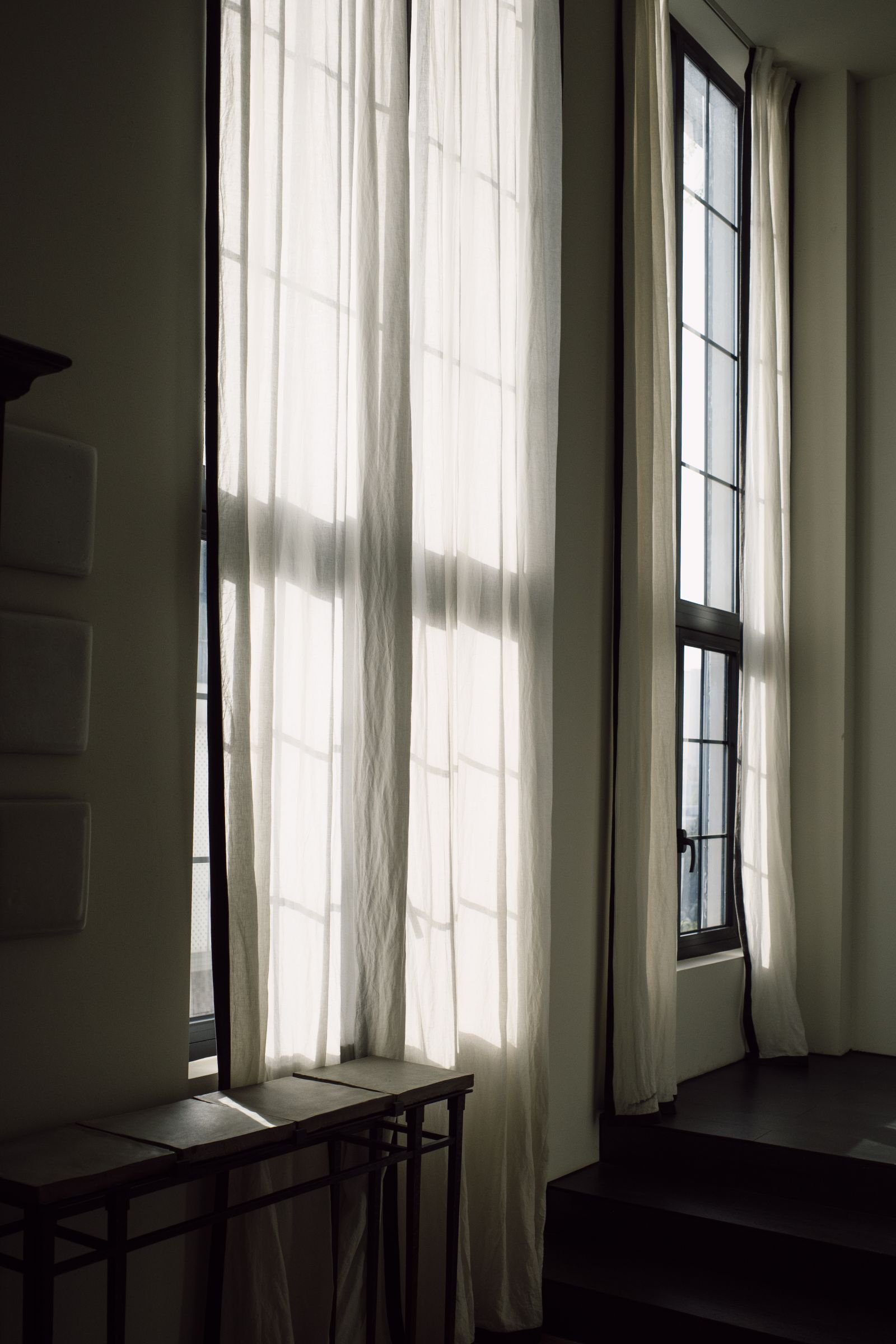 Sunlight filtering through tall sheer curtains in a minimalist room.