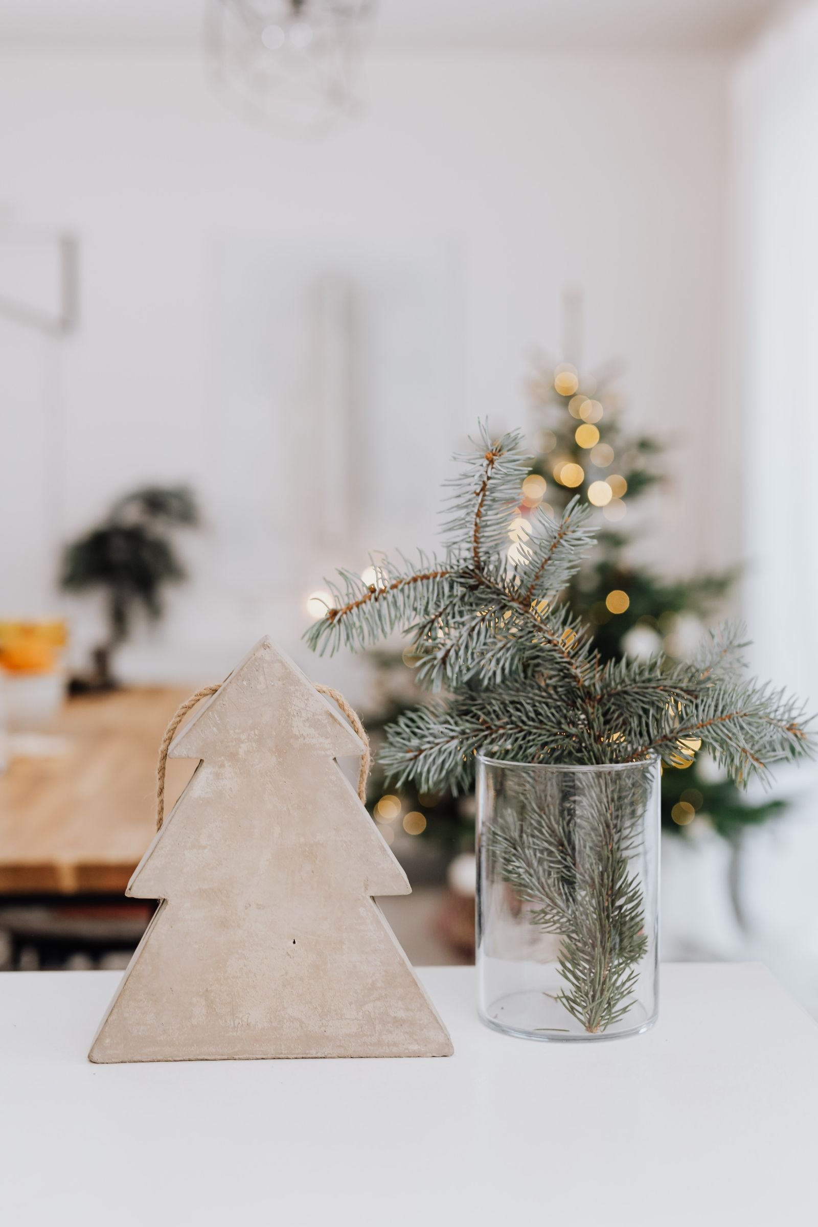 Small wooden Christmas tree beside a vase of fir branches.