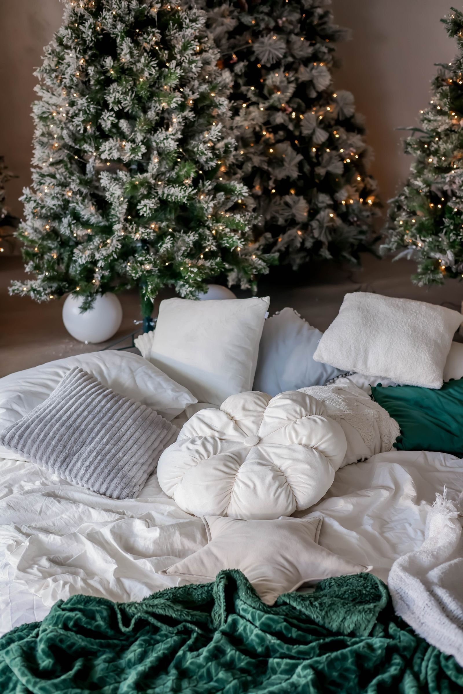 Cozy room with small Christmas trees, string lights and soft pillows.