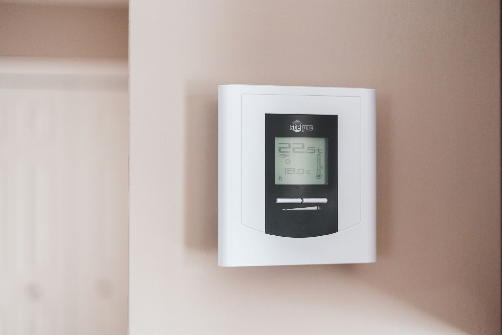 White digital thermostat mounted on a wall.