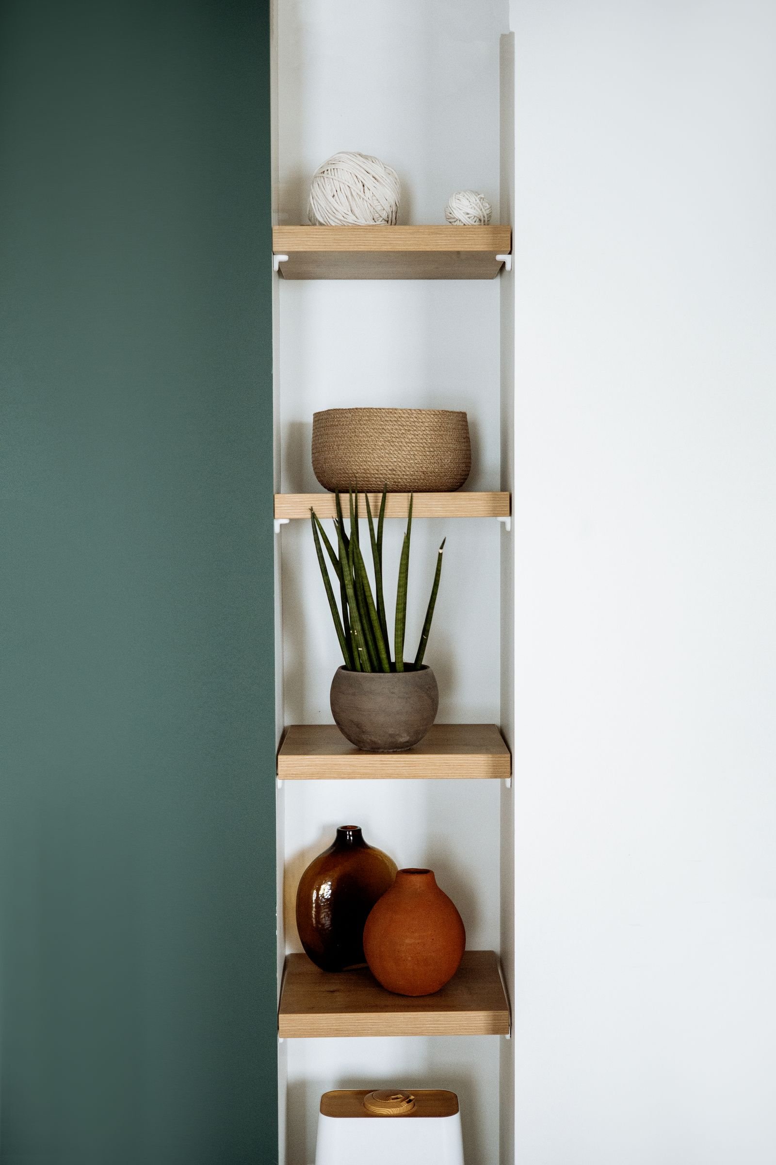 Wooden shelf with decorative vases and a small plant.