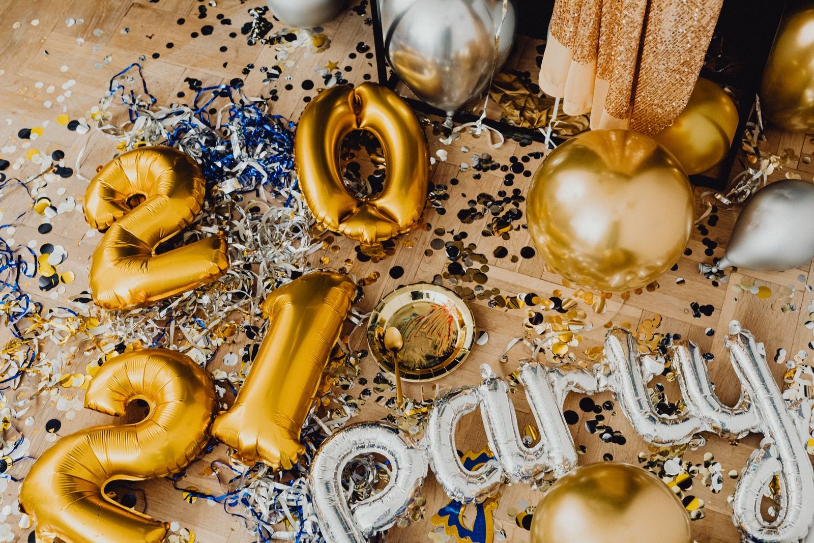 Gold and silver balloons and confetti scattered on the floor.