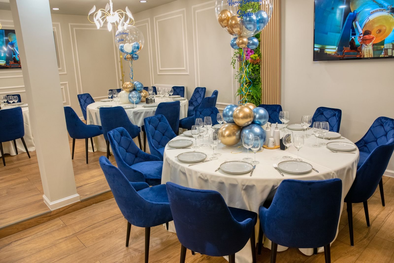 Dining room with blue chairs and balloon centerpieces.
