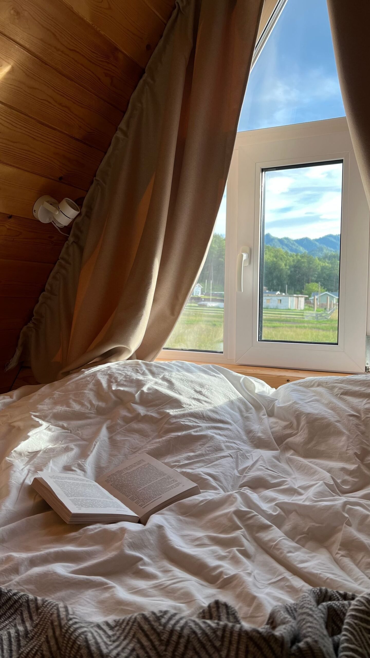 Sunlit bedroom with an open book on the bed by the window.