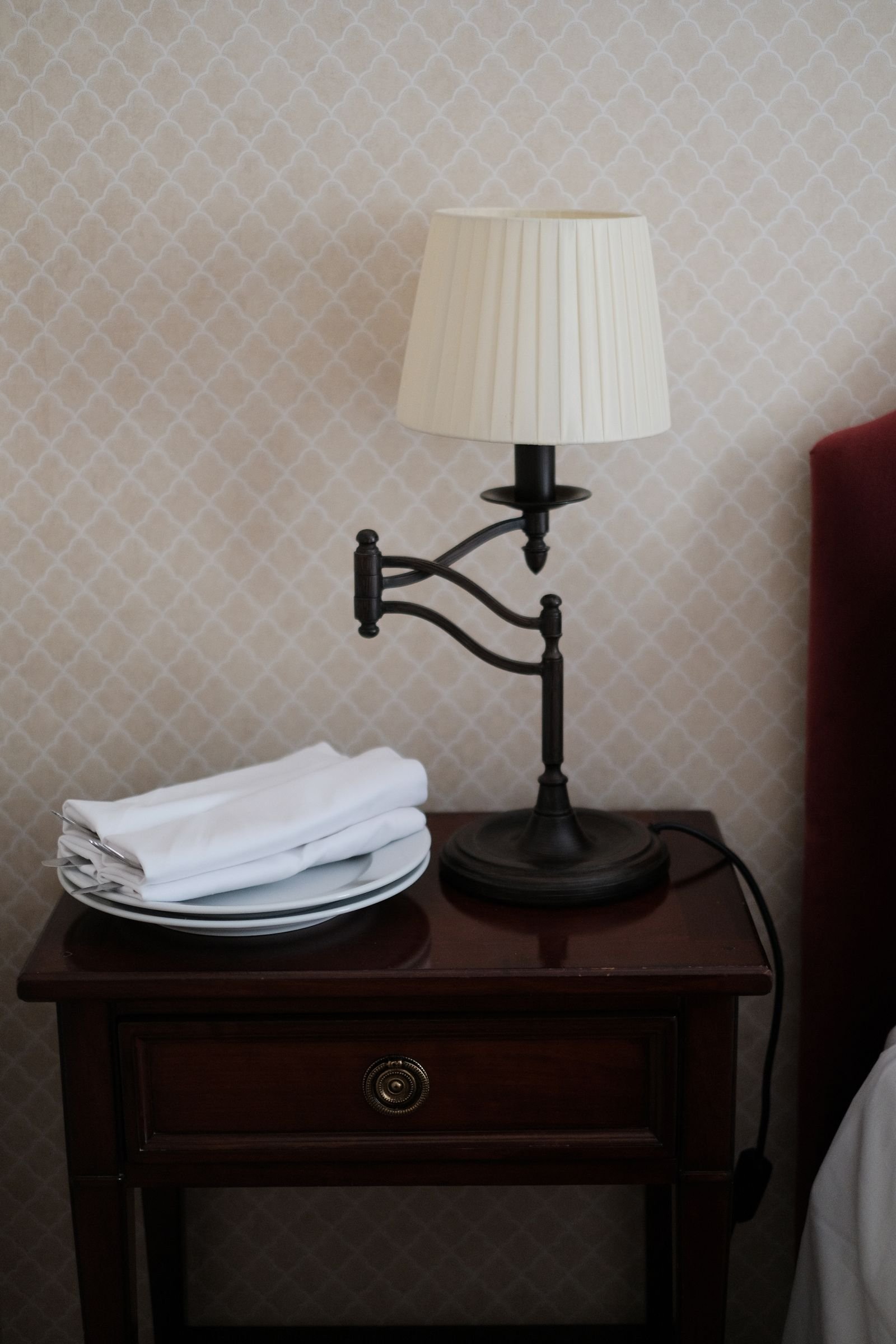 Neat bedside table with a classic lamp and folded linens.