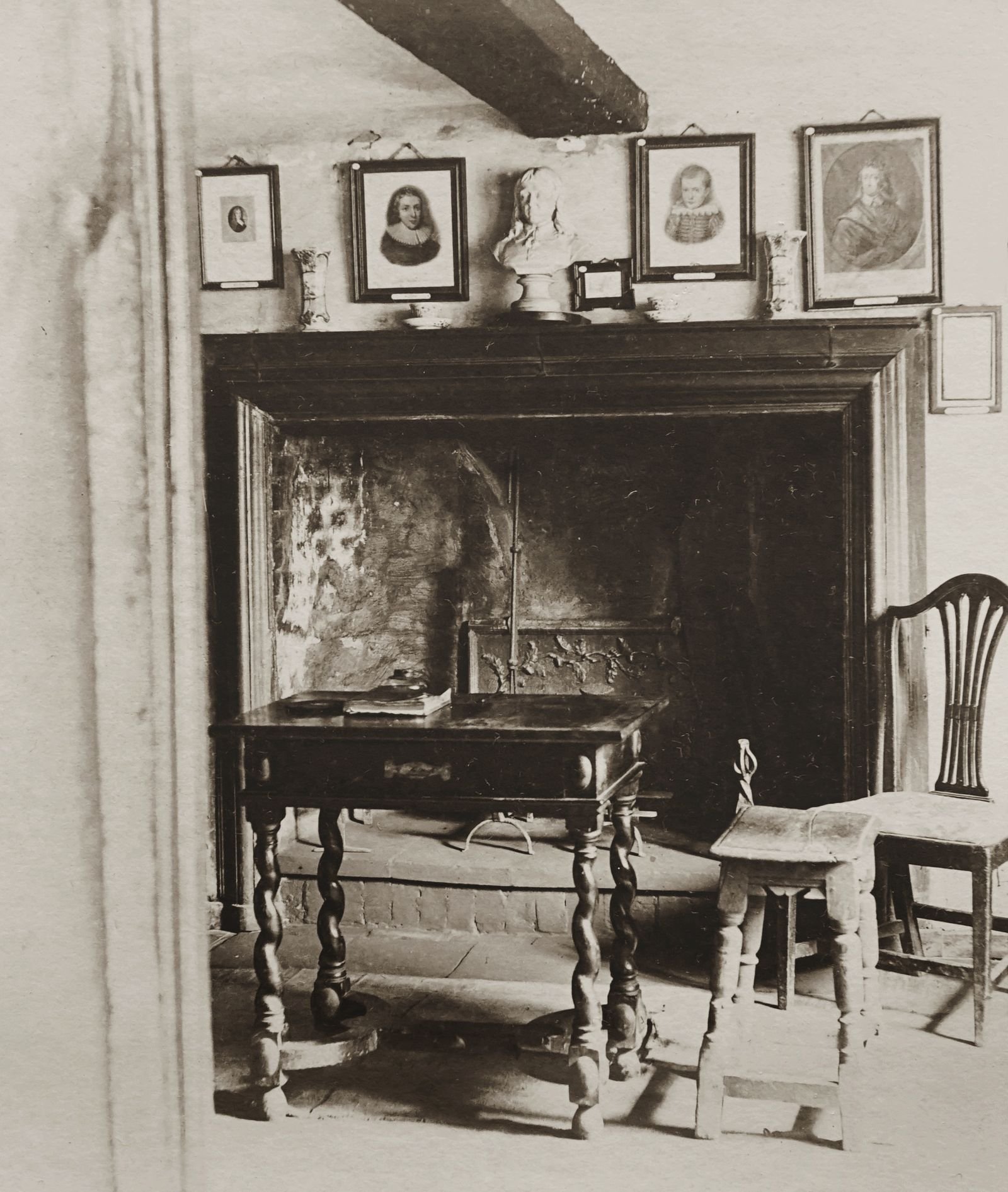 Vintage living room with antique furniture and picture frames by a fireplace.